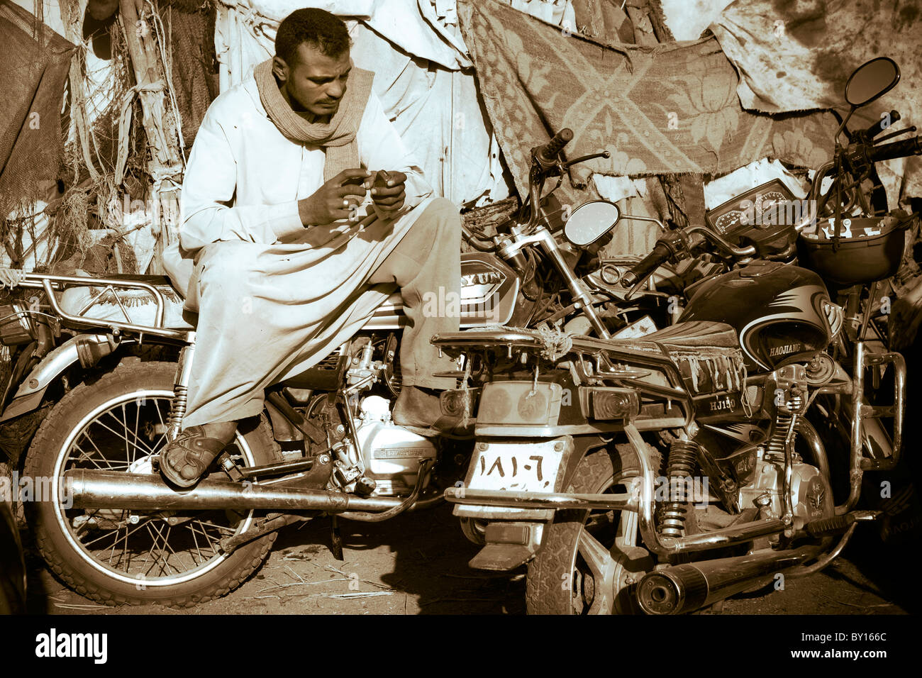 Seppia shot egiziano di uomo seduto sulla moto in settimanalmente il cammello e il mercato del bestiame nei pressi di Luxor, Egitto Foto Stock