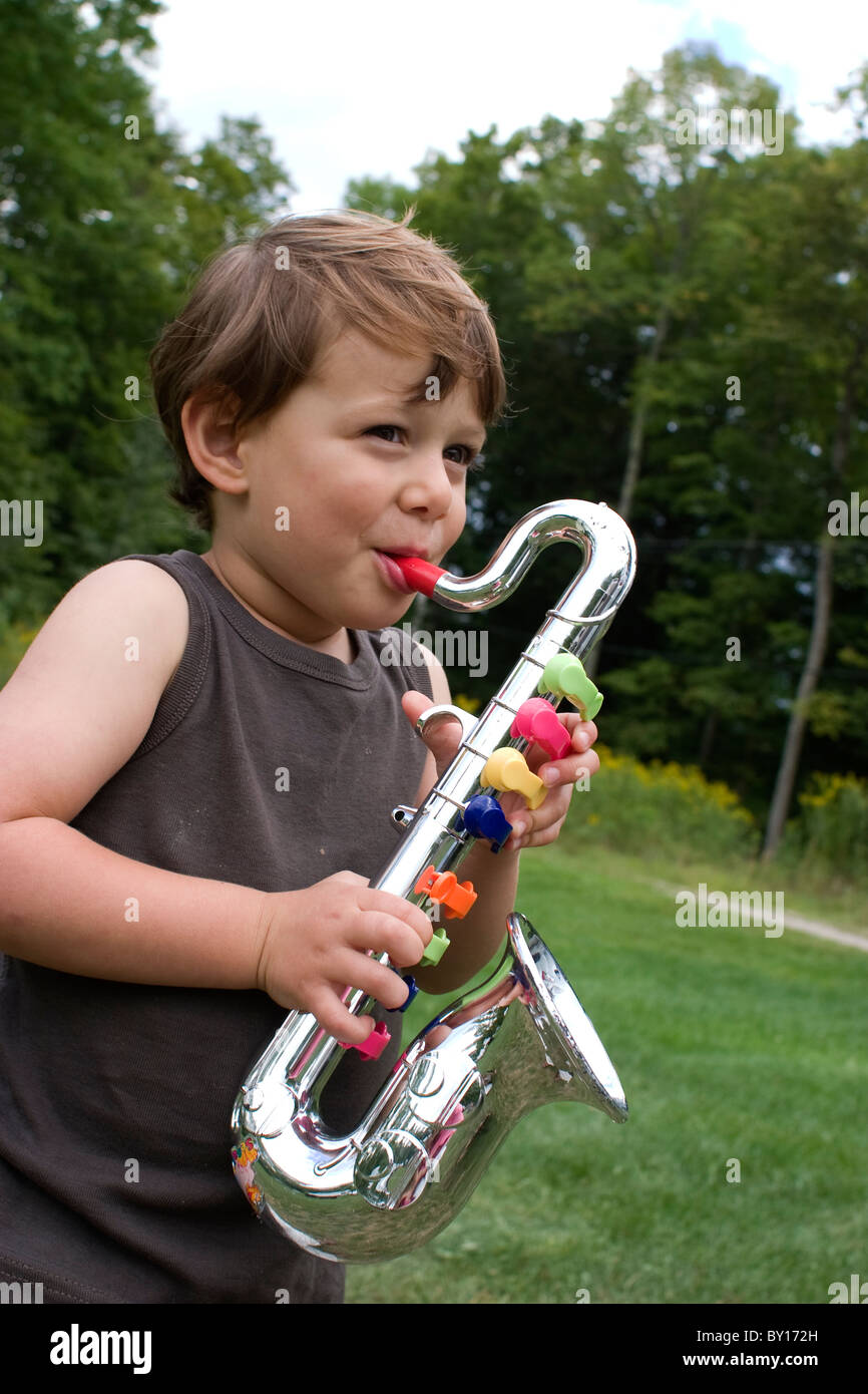 Un giovane ragazzo gode giocare il suo giocattolo sassofono all'esterno  Foto stock - Alamy