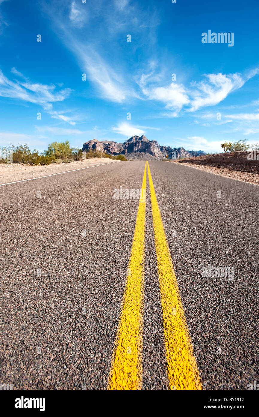 Una lunga strada vuota in un deserto remoto ubicazione lascia una diminuzione prospettiva. Foto Stock