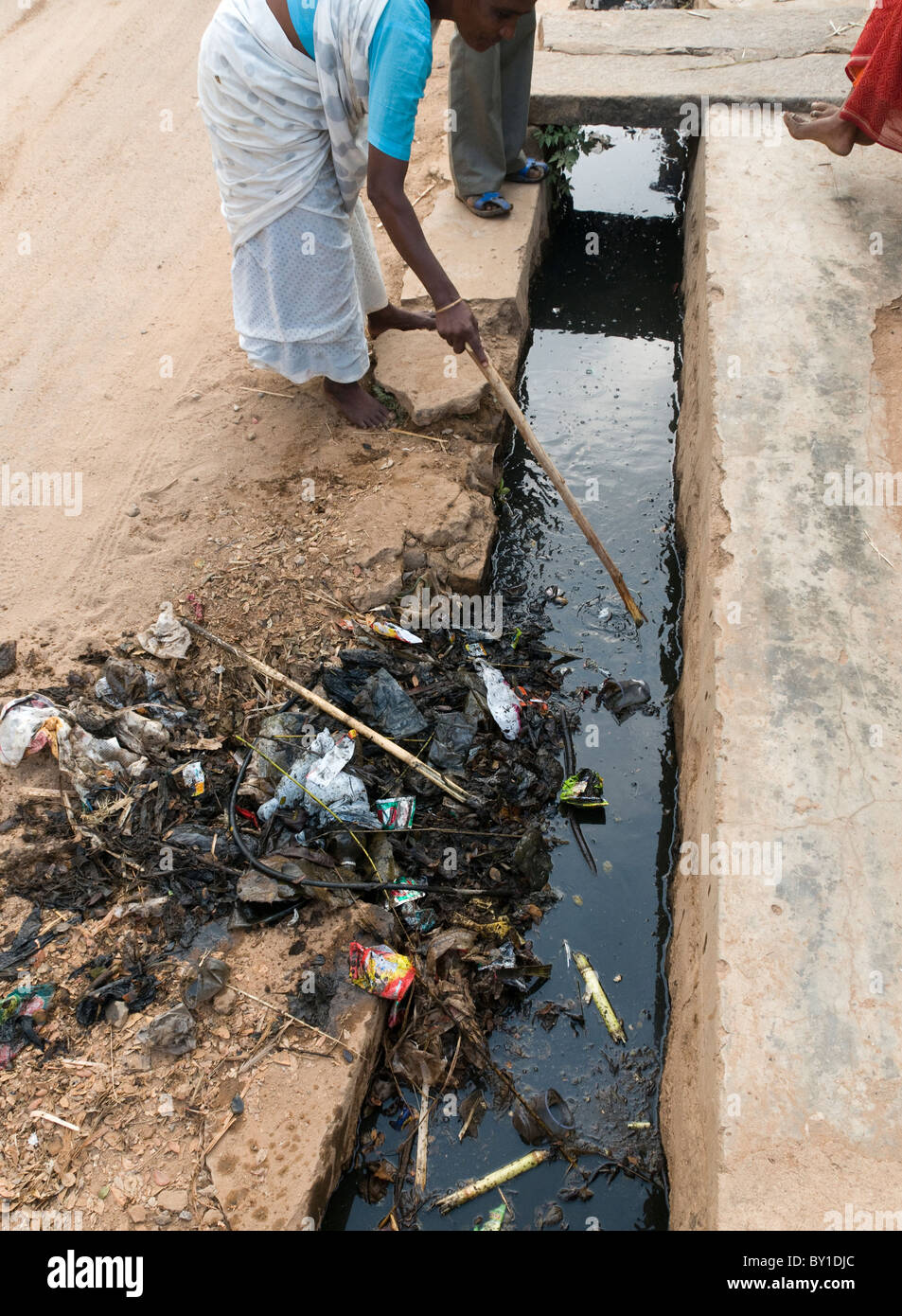 Sblocco di un tombino aperto sistema in una strada in India Foto Stock