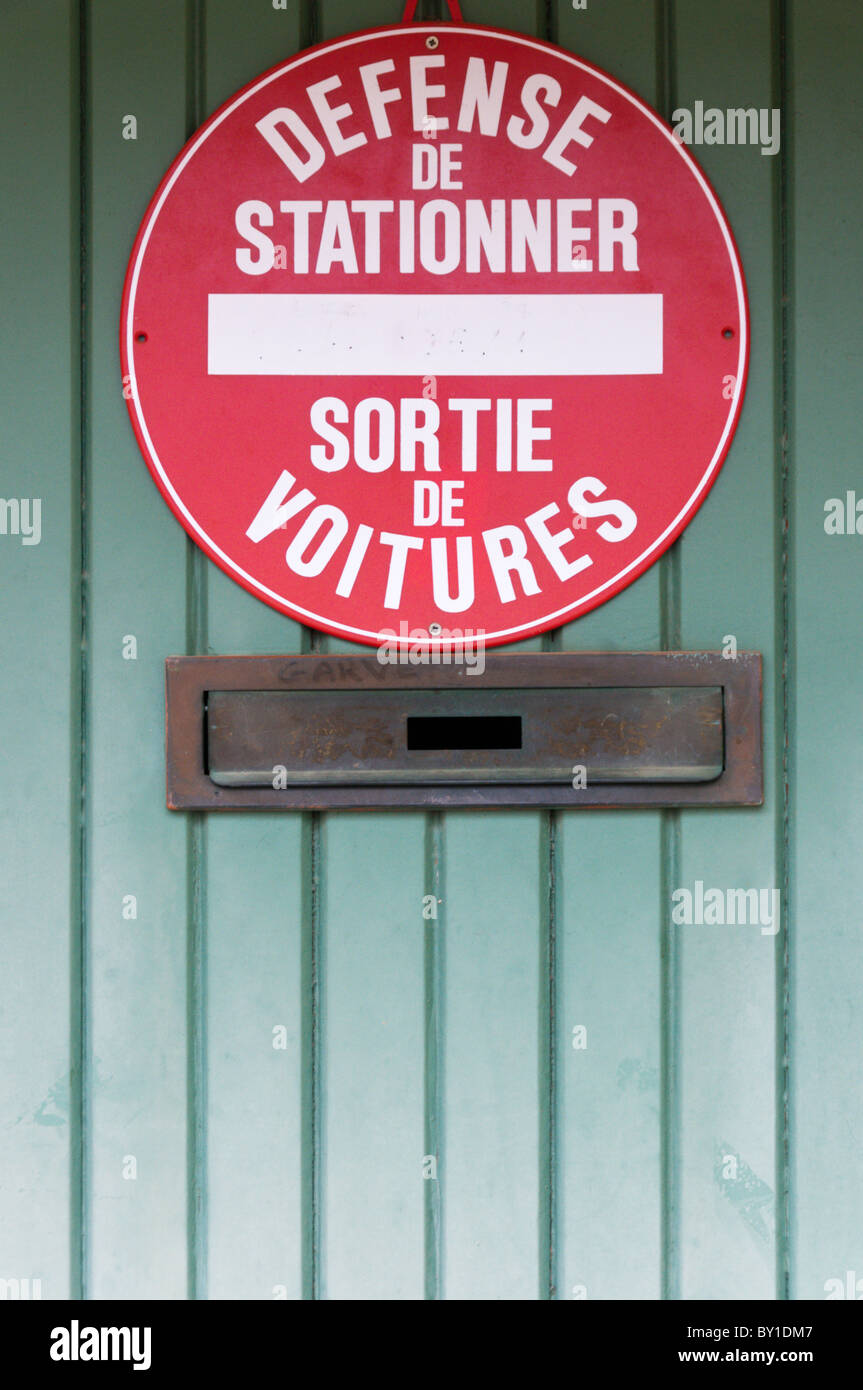 Il francese 'Defense De Stationner - Sortie de Voitures' (Nessun parcheggio - auto Uscire) firmare su porte di garage. Foto Stock