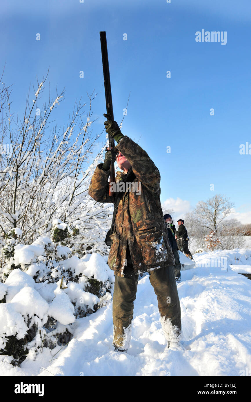 uomo che spara uccelli in un ambiente nevoso Foto Stock