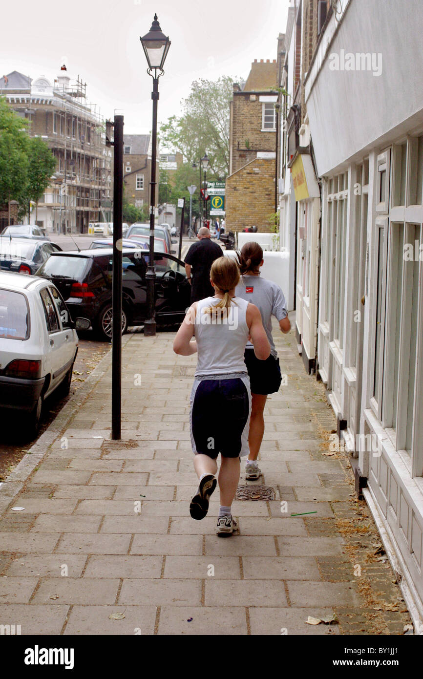 Due donne di jogging sul marciapiede della città Foto Stock