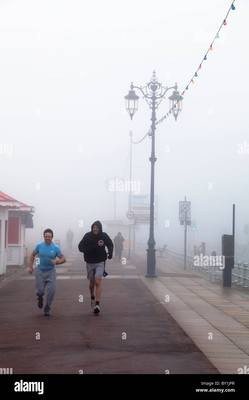 Jogging nella nebbia sul lungomare in inverno Foto Stock