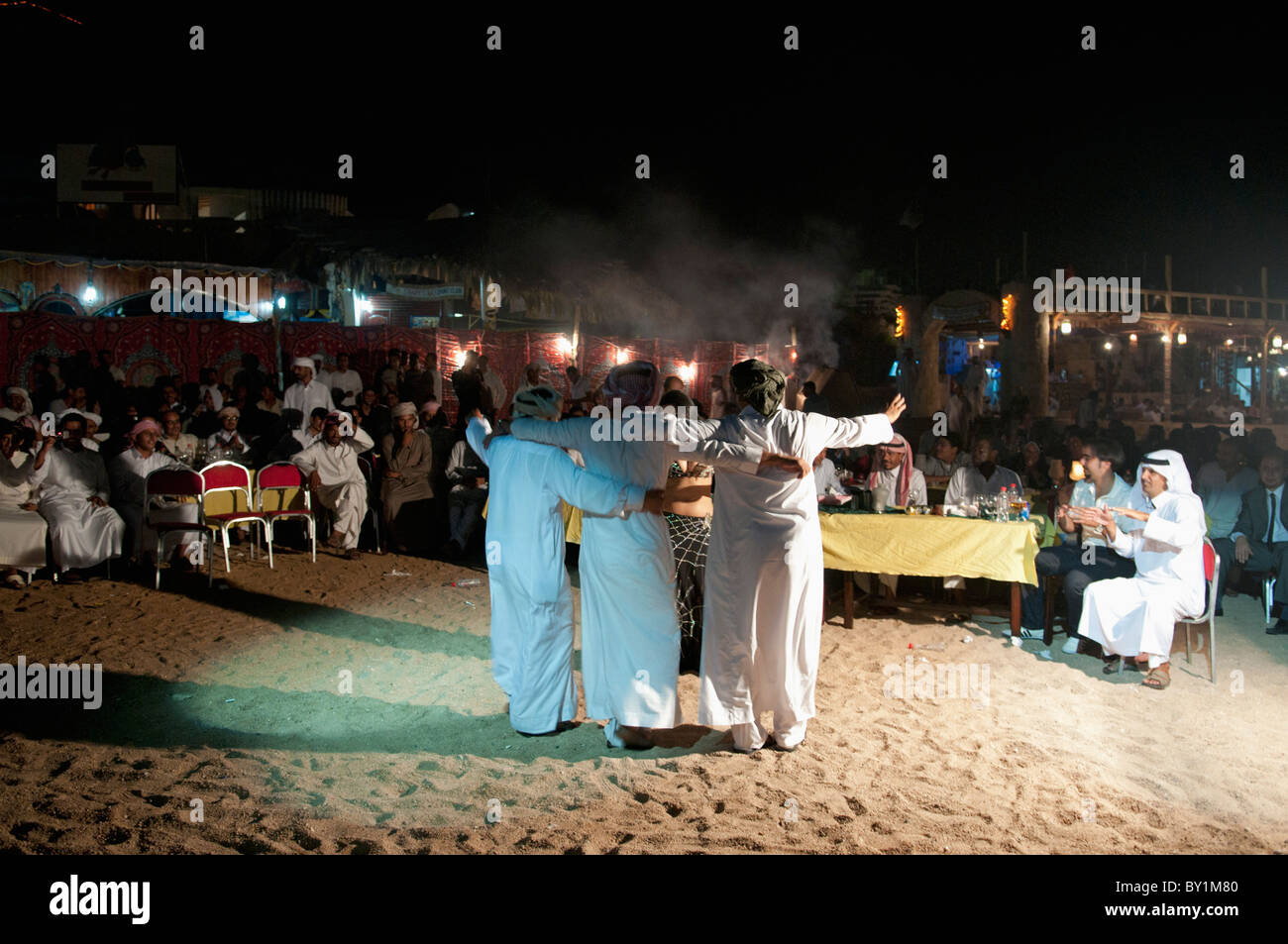 Gli uomini frequentano beduino tradizionale celebrazione dei matrimoni danza professionale con una danzatrice del ventre da Beirut come lei intrattiene gli ospiti. Foto Stock