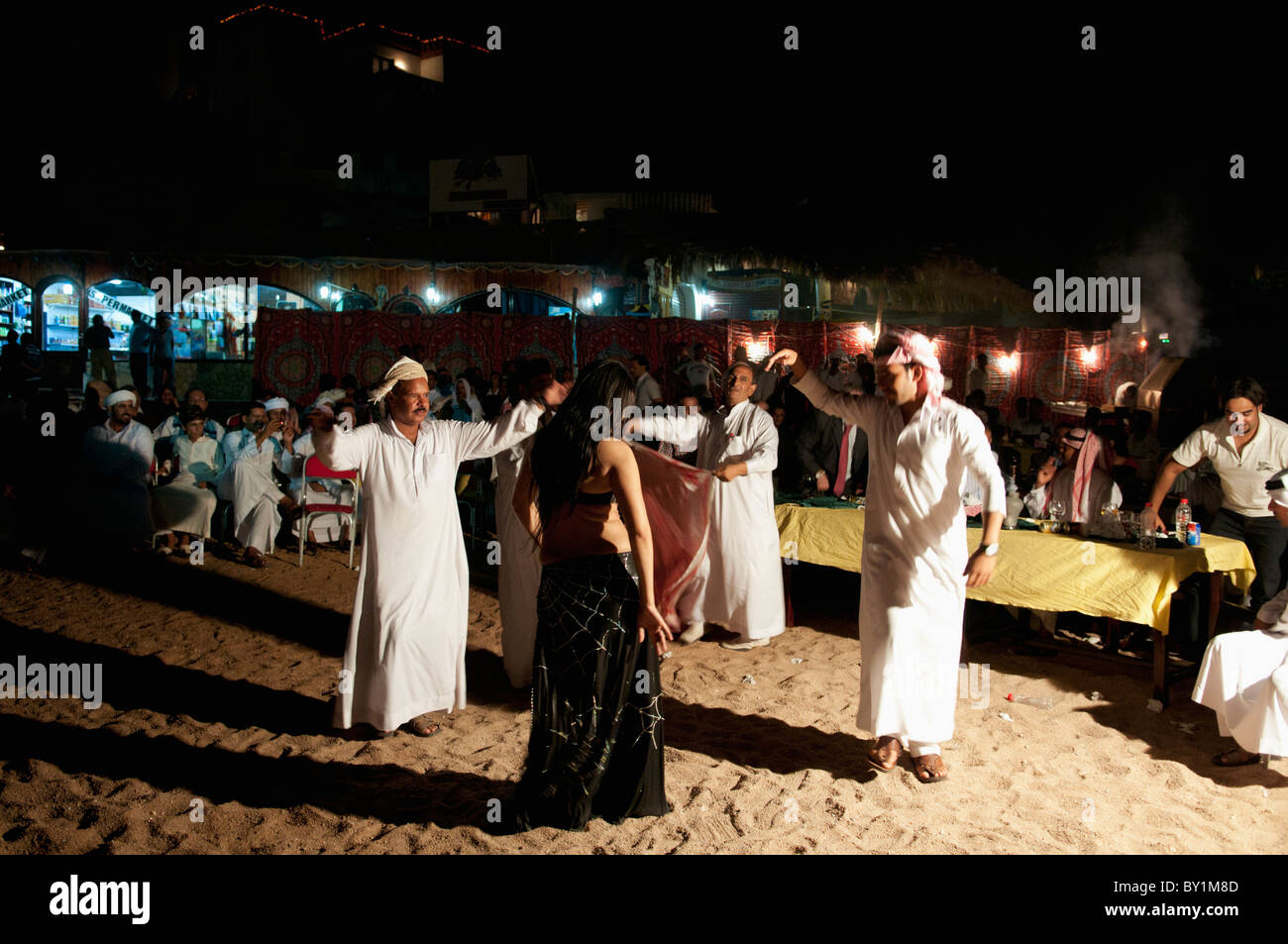 Gli uomini frequentano beduino tradizionale celebrazione dei matrimoni danza professionale con una danzatrice del ventre da Beirut come lei intrattiene gli ospiti. Foto Stock