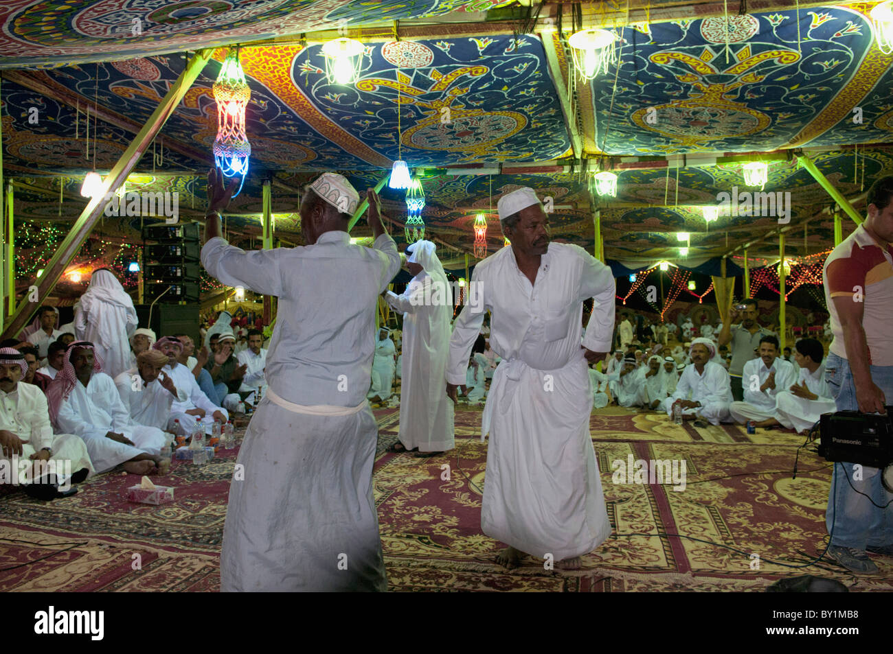 Gli ospiti celebrare con la danza come altri ospiti guardare durante un beduino tradizionale celebrazione di matrimonio. El Tur, Sinai, Egitto Foto Stock
