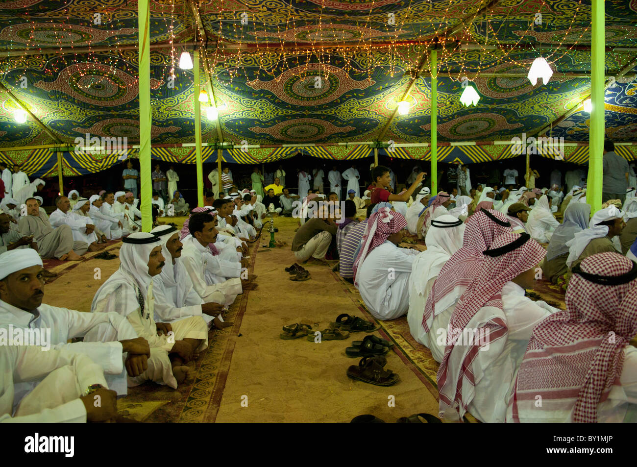 Ospiti seduti attendono intrattenimento durante un beduino tradizionale celebrazione di matrimonio. El Tur, Sinai, Egitto Foto Stock