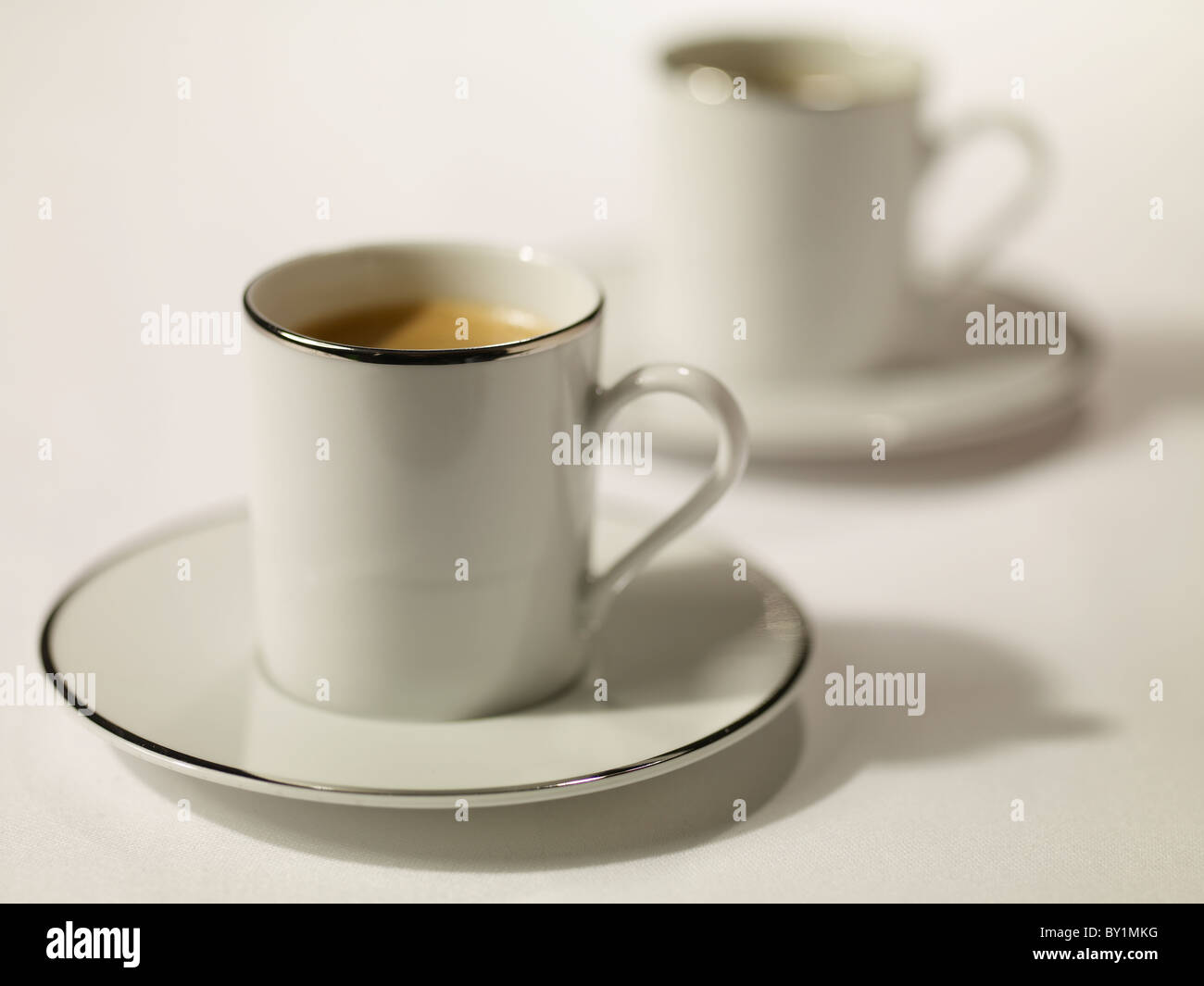 Nero caffè espresso in bianco le tazze con un argento dorato rim Foto Stock