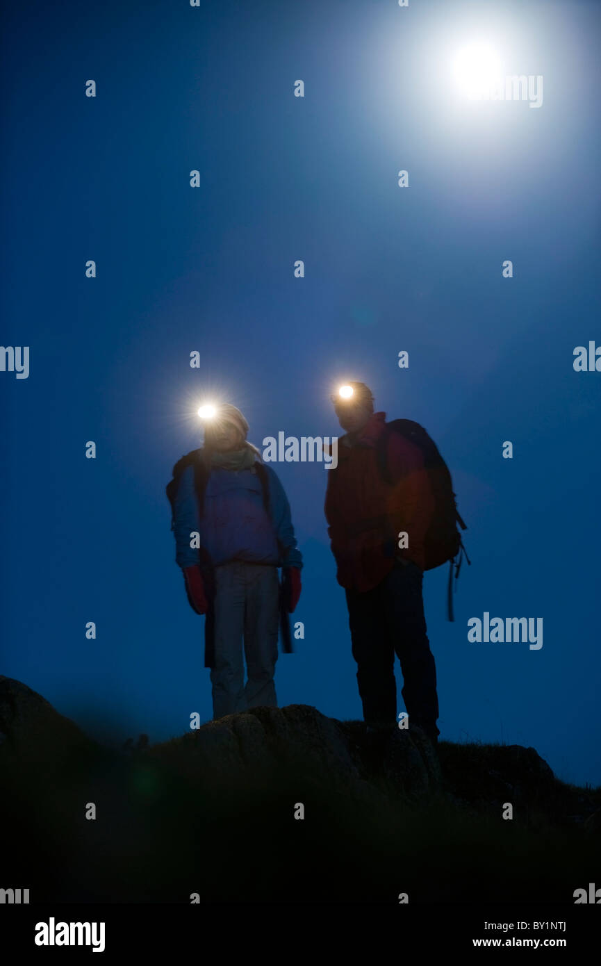 Gilar Farm, Snowdonia, il Galles del Nord. L uomo e la donna trekking di notte dalla torcia da testa a e moonlight. (MR) Foto Stock