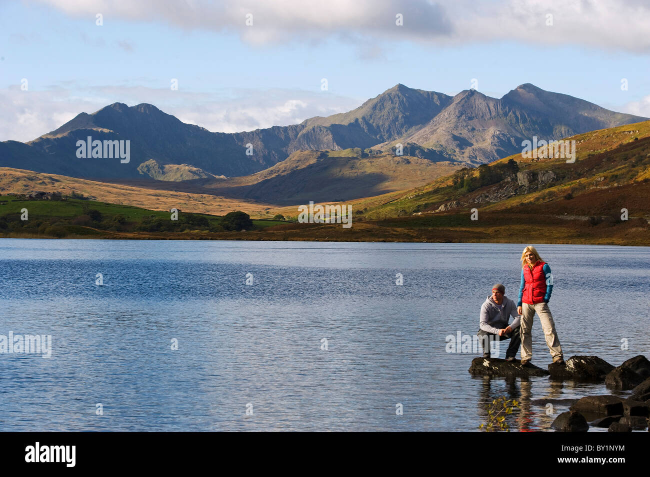 Il Regno Unito, il Galles del Nord, Snowdonia. L uomo e la donna stanno sulle rocce al bordo del Llyn Mymbyr con lo sfondo della Snowdon Foto Stock