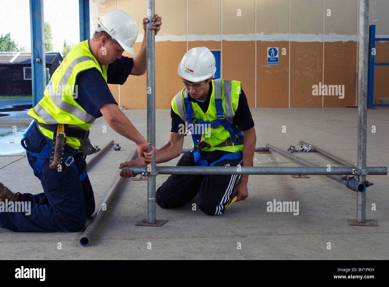 Costruzione di tirocinanti erigere impalcature poli Foto Stock