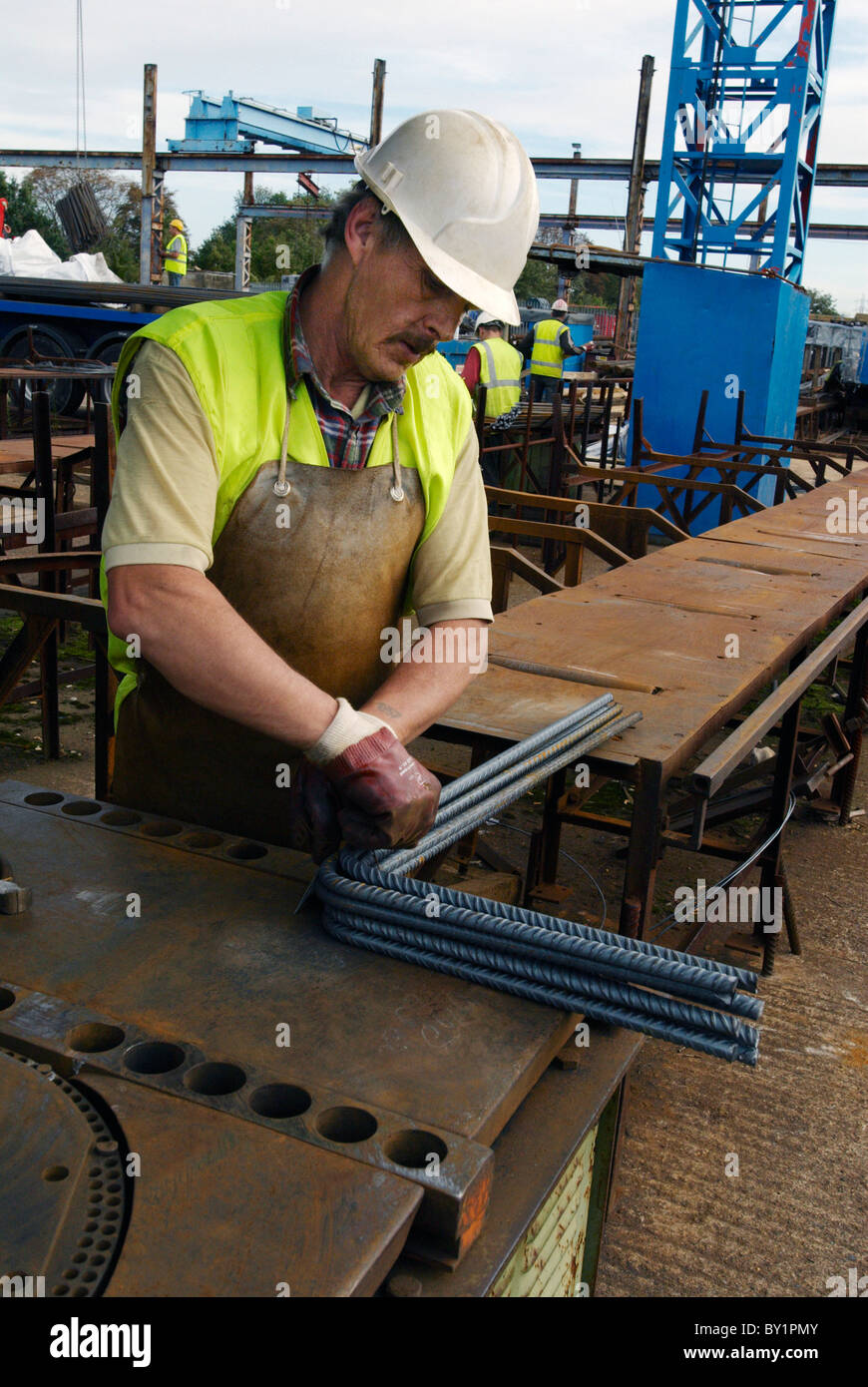 Il rinforzo del cemento armato: tondino di acciaio tagliati e piegati in fabbrica. Lavoratore piegatura di tondini di acciaio Foto Stock