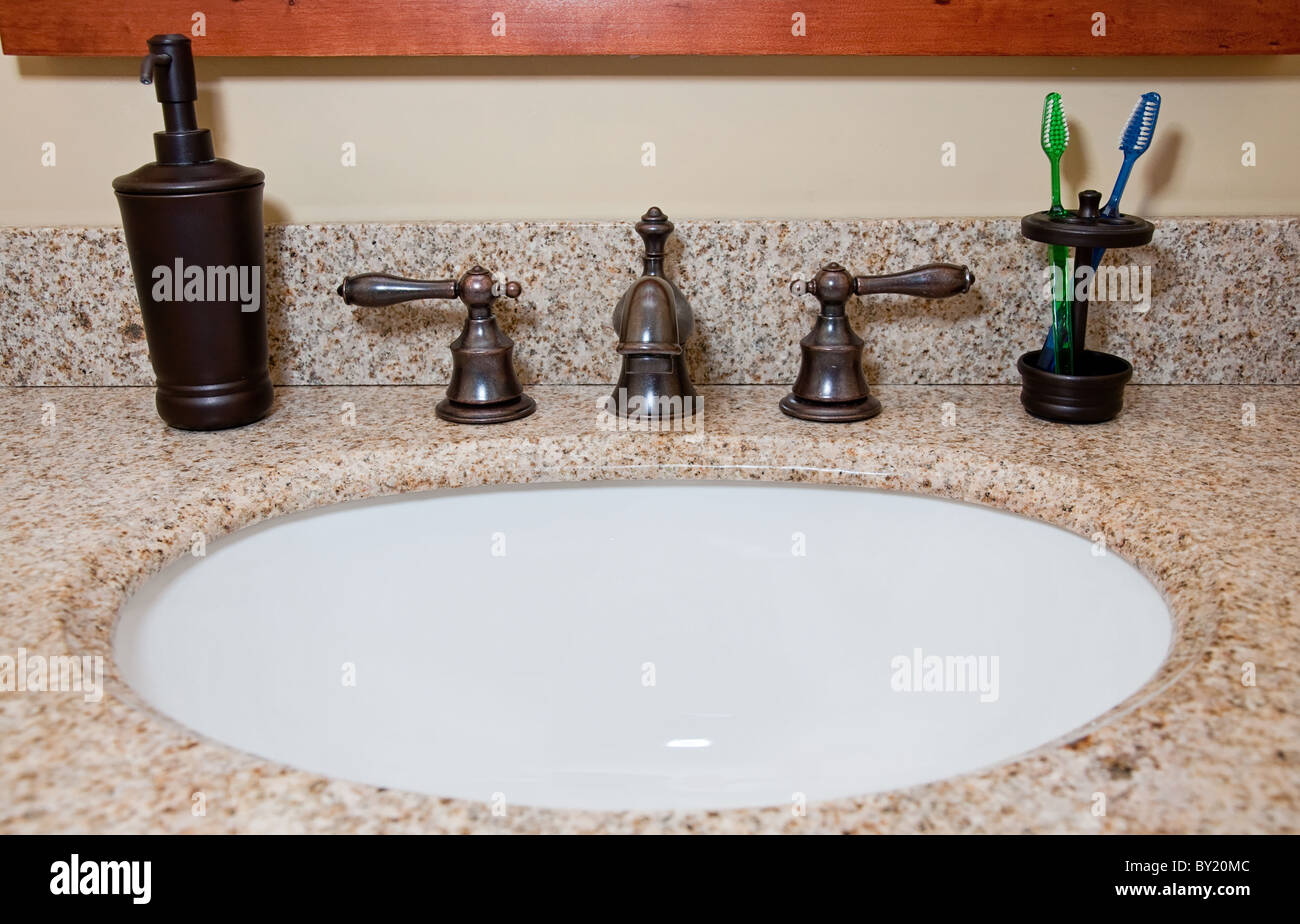 Il lavandino del bagno e il rubinetto con gli spazzolini da denti e dispensatore di sapone. Foto Stock