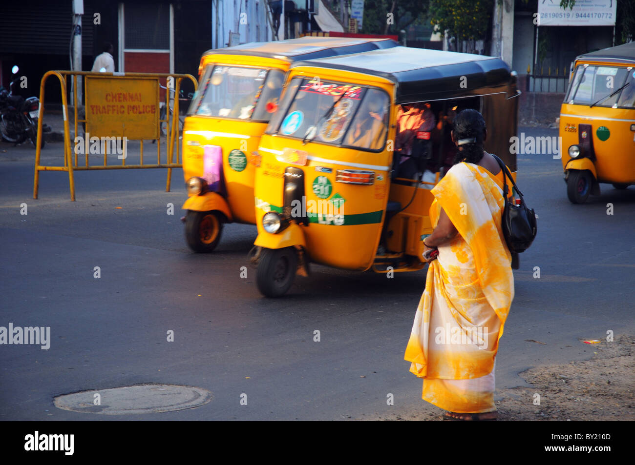 Una donna che indossa un sari giallo in attesa di attraversare la strada in India Foto Stock