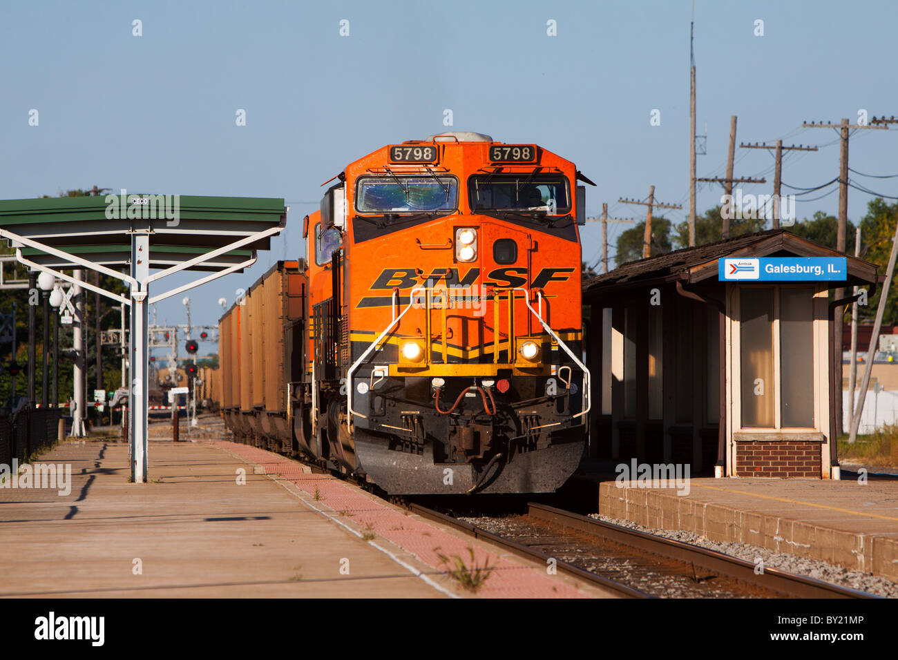 Una ferrovia BNSF carbone treno rotoli attraverso il deposito di Amtrak in Galesburg, IL. Foto Stock