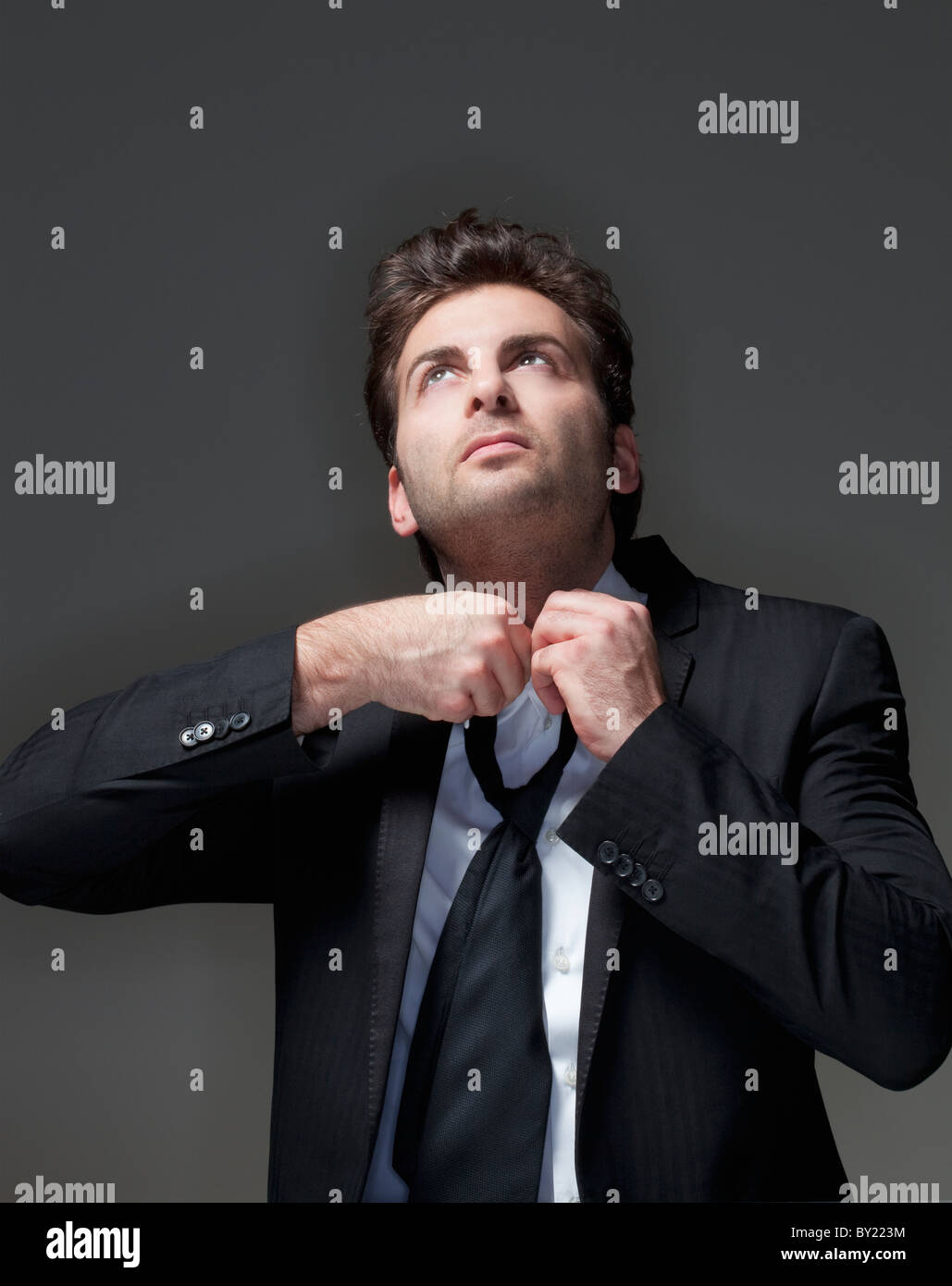 Imprenditore nel soddisfare allentando la cravatta - isolato su grigio Foto Stock