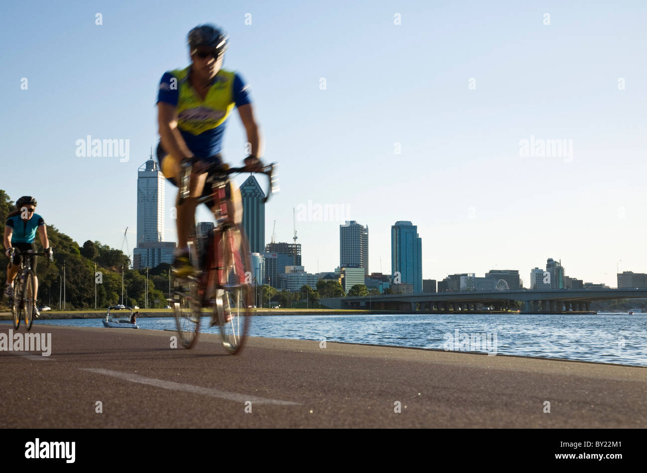 Australia, Western Australia Perth. Ciclista sul lungofiume di Perth con lo skyline della città al di là. Foto Stock