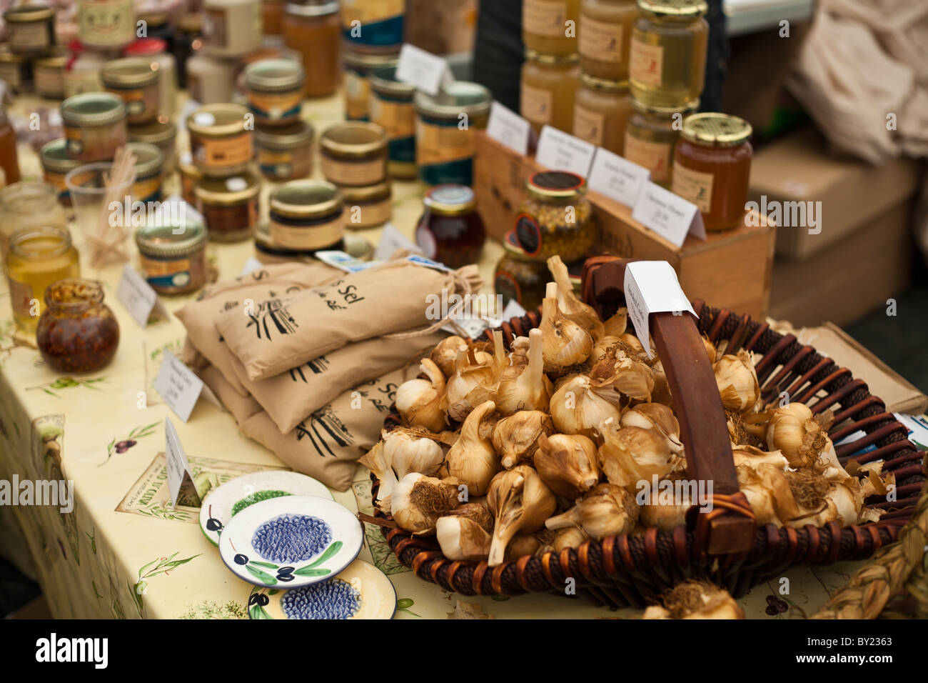 Inghilterra, Shropshire, Ludlow. Un display di marmellate e mostarde e un cesto pieno di aglio, a Ludlow Food Festival. Foto Stock
