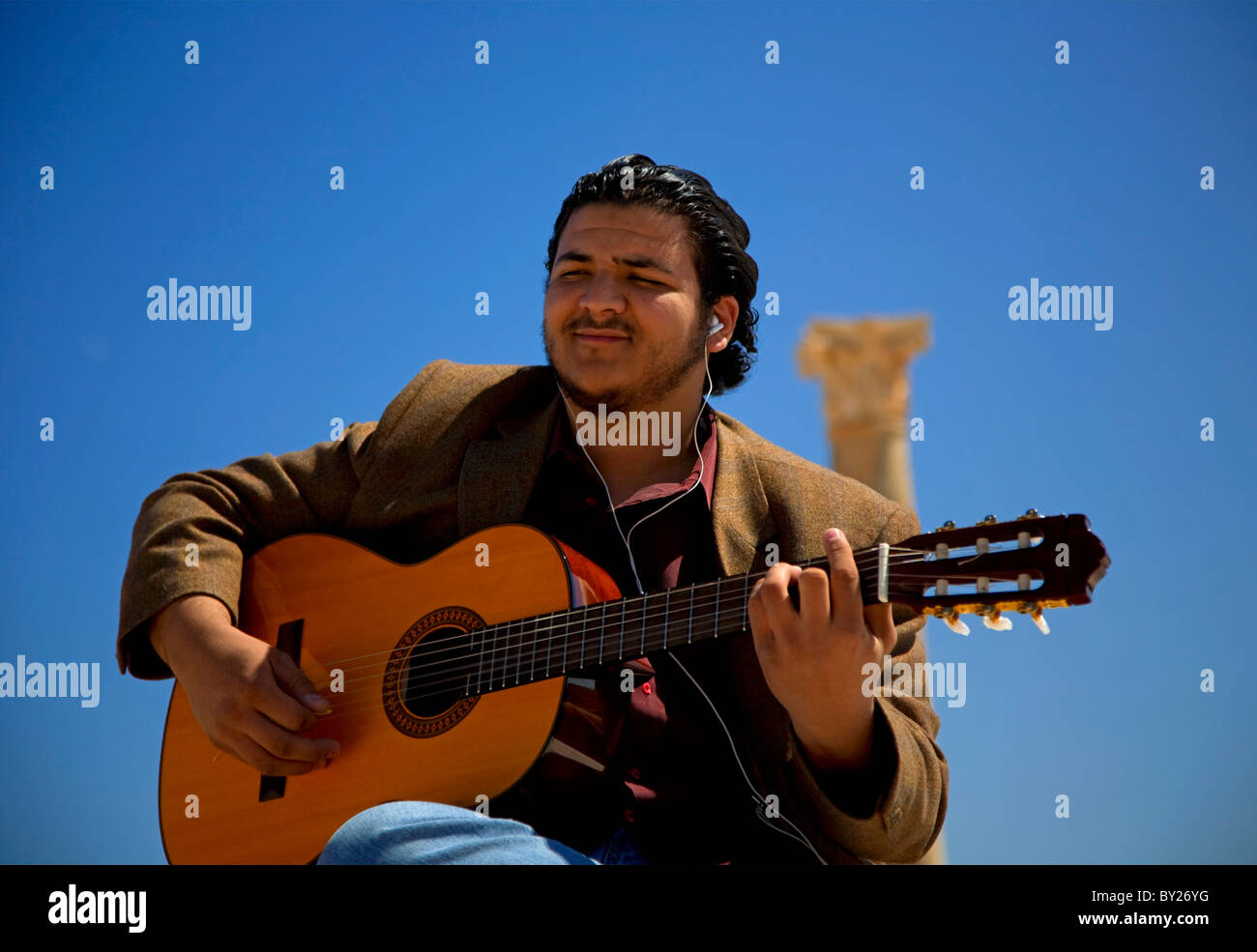 Sabratha, Libia; un giovane chitarrista libico giocando in Sabratha tra i resti della città romana Foto Stock