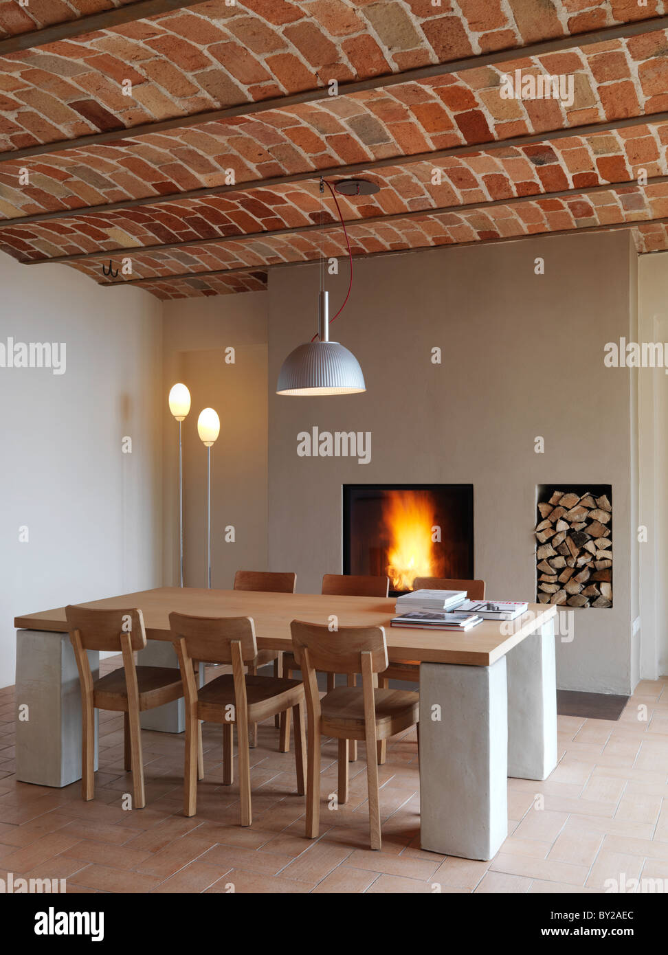 Tavolo moderno con sei sedie di legno davanti a un caminetto con un  pavimento in piastrelle di cotto e soffitto in mattoni Foto stock - Alamy