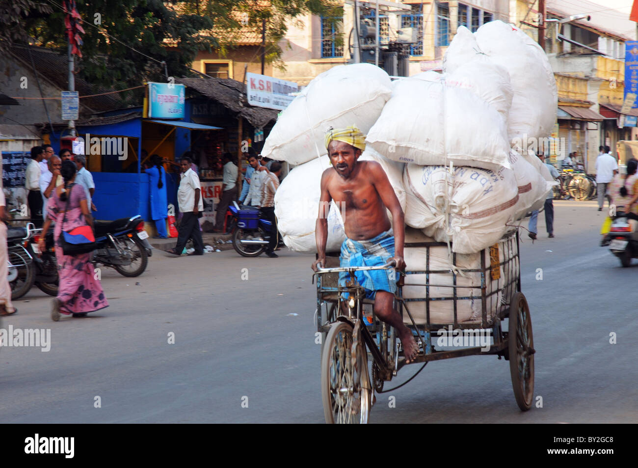 Un pedale rickshaw tirando un enorme carico in India Foto Stock