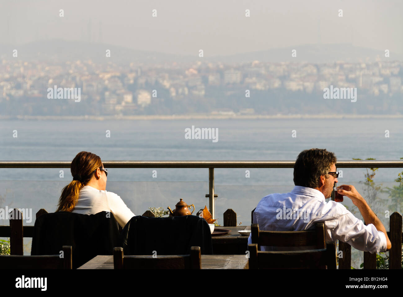Tè turco, vista sul Bosforo Gulhane Park Istanbul // ISTANBUL, Turchia - i turisti amano sorseggiare il loro tè turco mentre si godono una vista sul Bosforo nel Parco Gulhane accanto al Palazzo Topkapi. Il tranquillo ambiente all'aperto offre un punto panoramico perfetto per osservare la vivace città dall'altra parte dell'acqua. Foto Stock