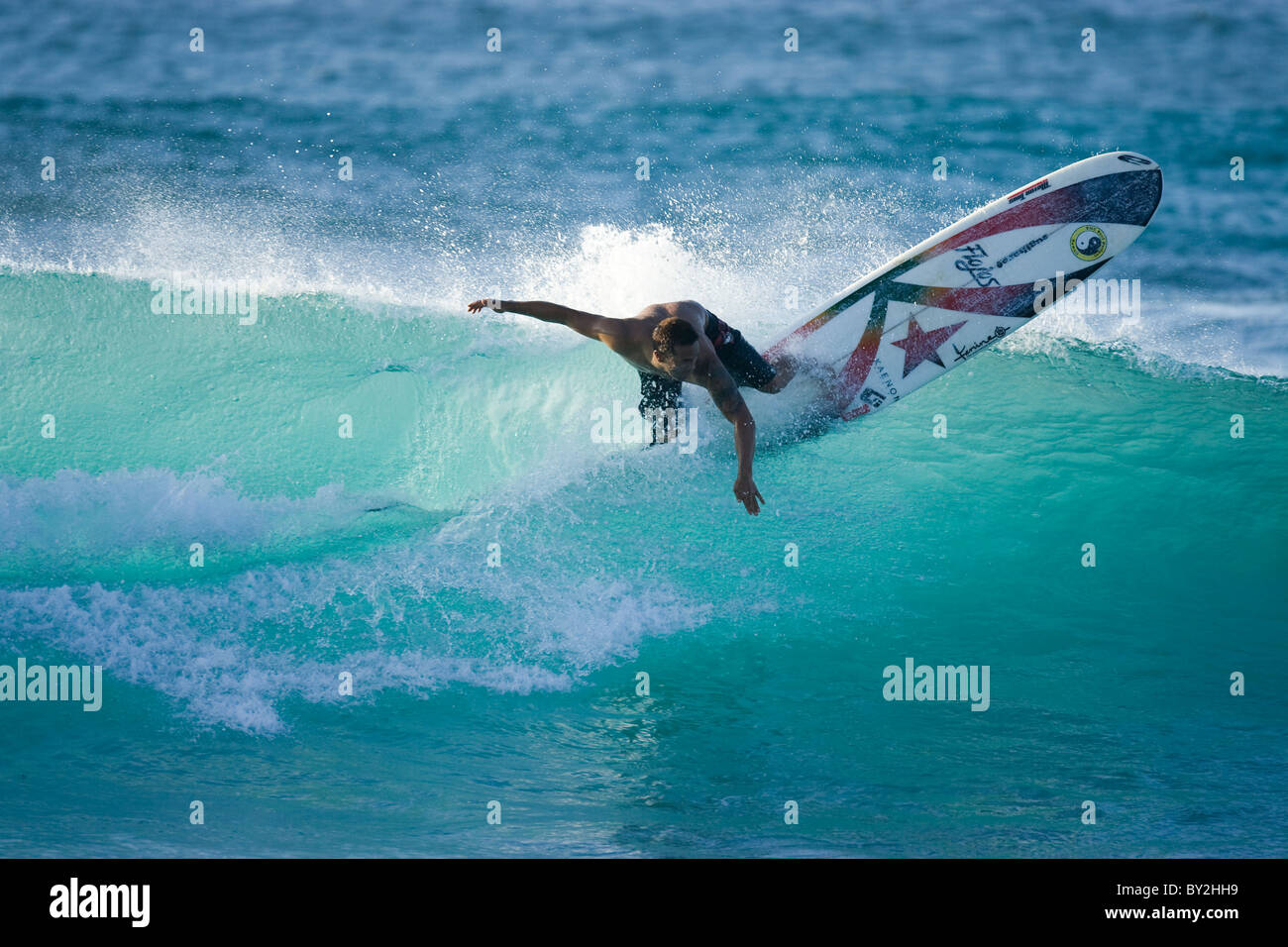 Un giovane uomo surf su un longboard Rocky Point, sulla North Shore di Oahu, Hawaii. Foto Stock