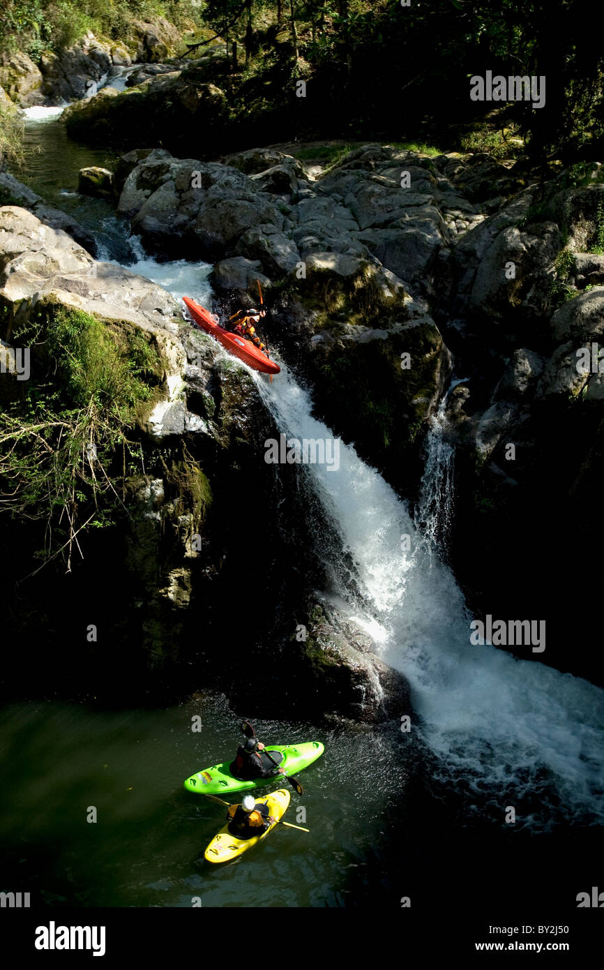 Due kayakers guardando un altro kayaker andare fuori di una cascata. Foto Stock