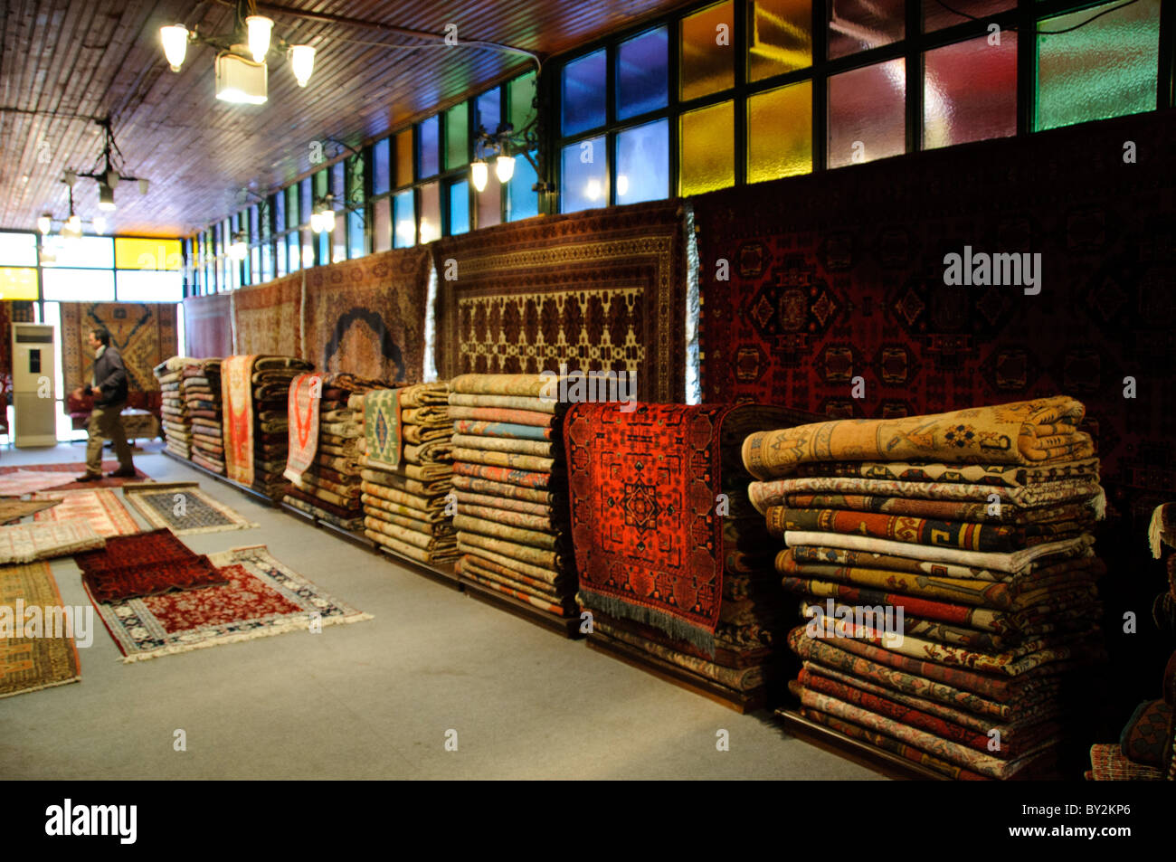 Tappeti turchi Arasta Bazaar Istanbul // ISTANBUL, Turchia - interno di un negozio di tappeti turchi presso l'Arasta Bazaar, un piccolo mercato coperto situato accanto alla Moschea del Sultano Ahmed (nota anche come Moschea Blu) nel quartiere Sultanahmet di Istanbul. L'Arasta Bazaar, costruito all'inizio del XVII secolo come parte del complesso della Moschea del Sultano Ahmed, è stato originariamente progettato per generare entrate per la manutenzione della moschea attraverso il reddito di affitto dai suoi negozi. Il bazar è specializzato in artigianato turco tradizionale, tessuti e tappeti, servendo sia i turisti che la gente del posto. La Moschea del Sultano Ahmed, c Foto Stock