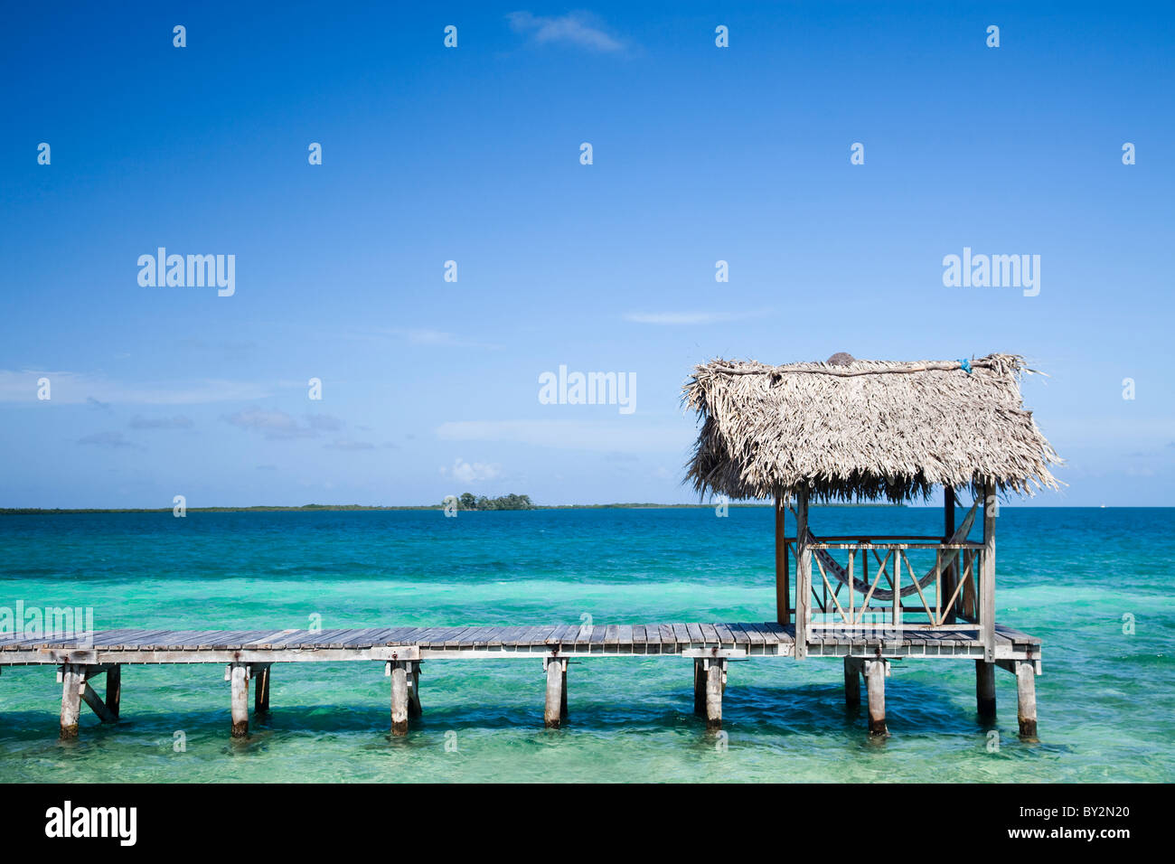 Una immagine panoramica di una passerella, amache e le cristalline blu, verdi acque dei Caraibi. Foto Stock