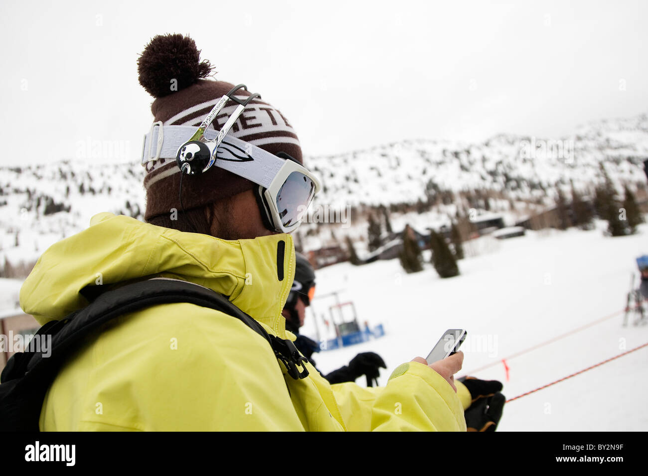 Un professionista di big mountain sciatore trova la canzone giusta sul suo ipod prima di salire sulla seggiovia in Alta, Utah. Foto Stock