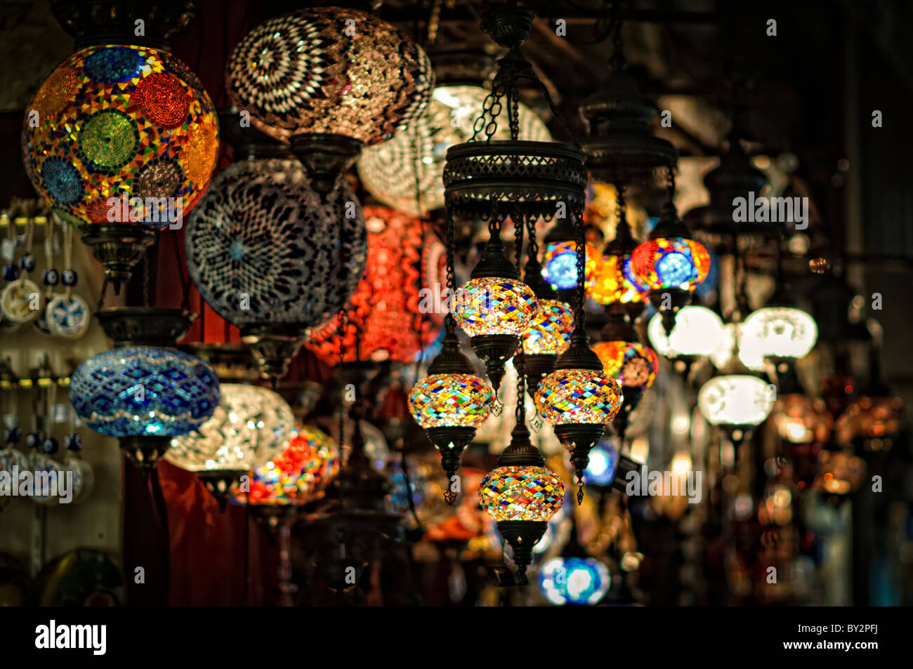 Lampade in vetro a mosaico Grand Bazaar Istanbul // ISTANBUL, Turchia - vivaci lampade in vetro a mosaico illuminano un negozio nello storico Grand Bazaar di Istanbul. La gamma colorata di lampade tradizionali turche crea un'abbagliante esposizione di artigianato artigianale. Queste lampade distintive, che combinano vetro colorato e metallo, rappresentano uno dei molti mestieri tradizionali disponibili in questo mercato secolare. Foto Stock