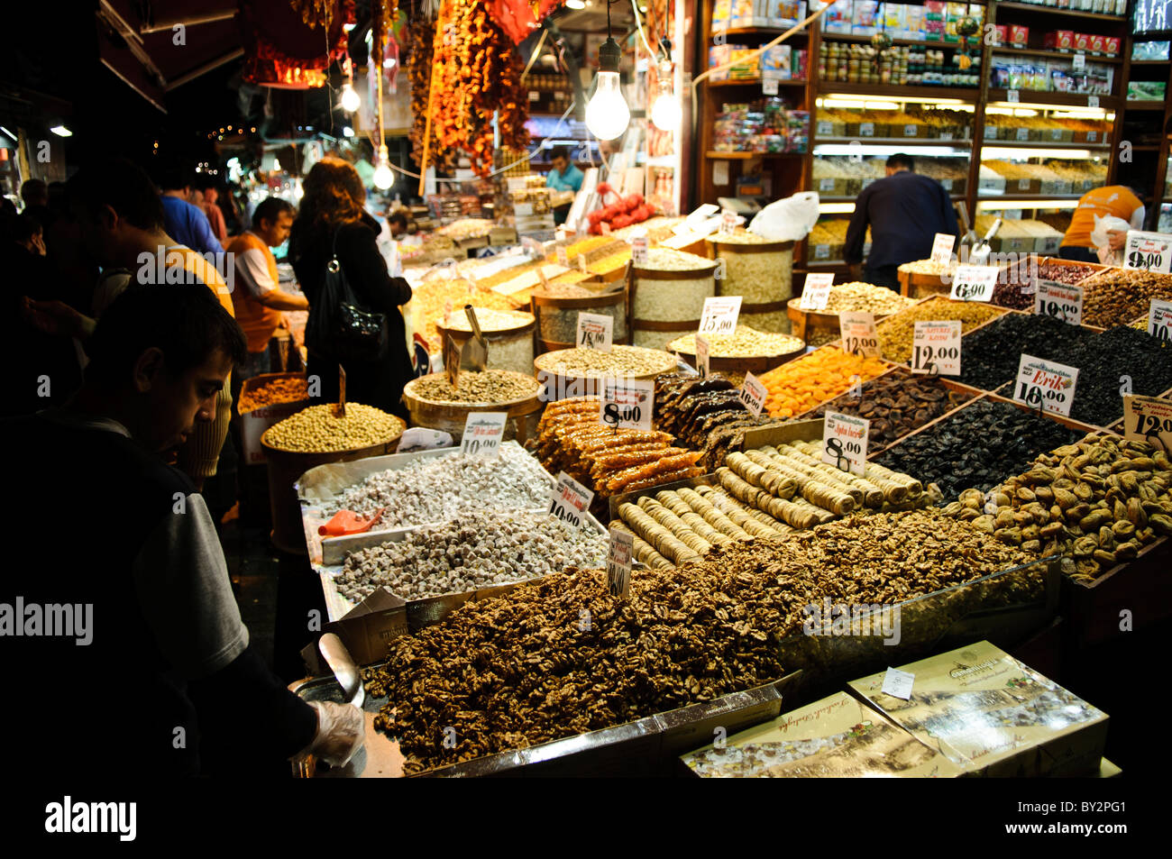 Spice Bazaar Nuts and Dried Fruits Istanbul // ISTANBUL, Turchia — frutta secca assortita e altri articoli esposti all'esterno di un negozio adiacente al Bazaar delle spezie (noto anche come Bazaar egiziano) a Istanbul. Il Bazar delle spezie, costruito nel 1660, è uno dei più antichi mercati coperti di Istanbul e un importante centro per il commercio di spezie, tè e prodotti secchi. Situato nel quartiere di Eminönü, vicino al Corno d'Oro, il bazar attrae sia la gente del posto che i visitatori internazionali alla ricerca di prelibatezze e ingredienti tradizionali turchi. I 88 negozi del mercato offrono un'ampia varietà di spezie, delig turco Foto Stock