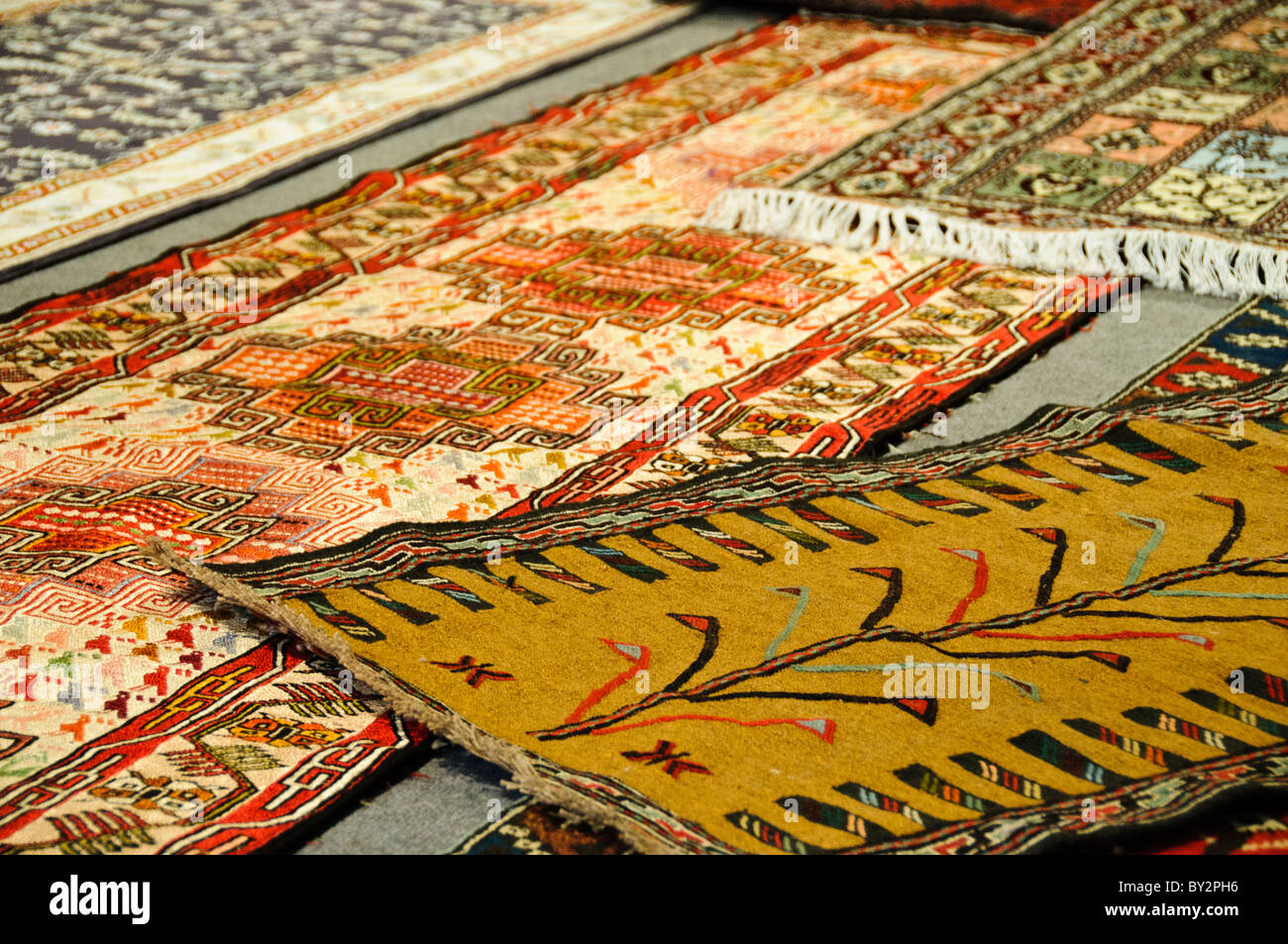 Tappeti turchi Arasta Bazaar Istanbul // ISTANBUL, Turchia — disegni di tappeti turchi esposti presso l'Arastar Bazaar, un piccolo mercato situato accanto a Sultanahmet Camii (noto anche come la Moschea Blu). L'Arastar Bazaar è una delle zone commerciali tradizionali di Istanbul, specializzata in tappeti, tessuti e artigianato. Sultanahmet Camii, completato nel 1616 durante il regno del sultano Ahmed i, è rinomato per le sue distintive piastrelle blu Iznik e sei minareti. La vicinanza del bazar a questa grande moschea dell'epoca ottomana lo rende una destinazione popolare per i visitatori che esplorano la setta di Istanbul Foto Stock