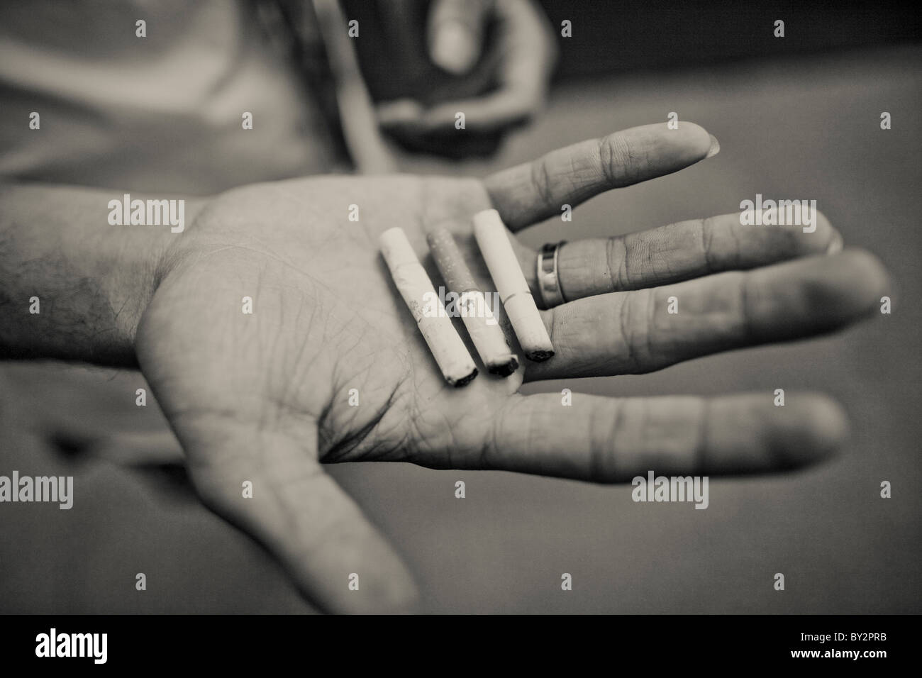 Un senzatetto giovane adulto contiene mozziconi di sigaretta, o Foto Stock