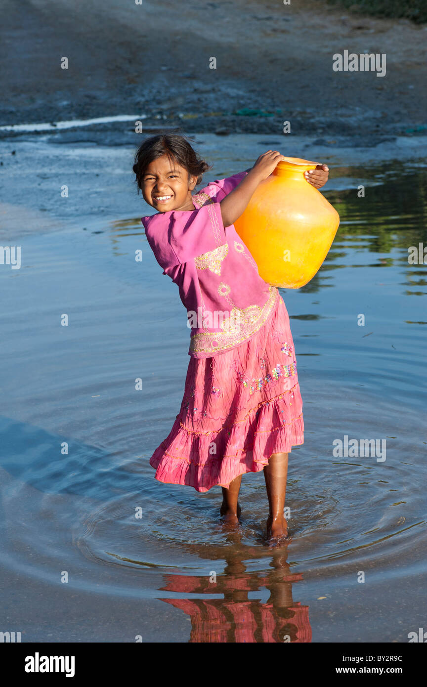 Sorridendo felice villaggio indiano ragazza che porta una pentola d'acqua. Andhra Pradesh, India Foto Stock