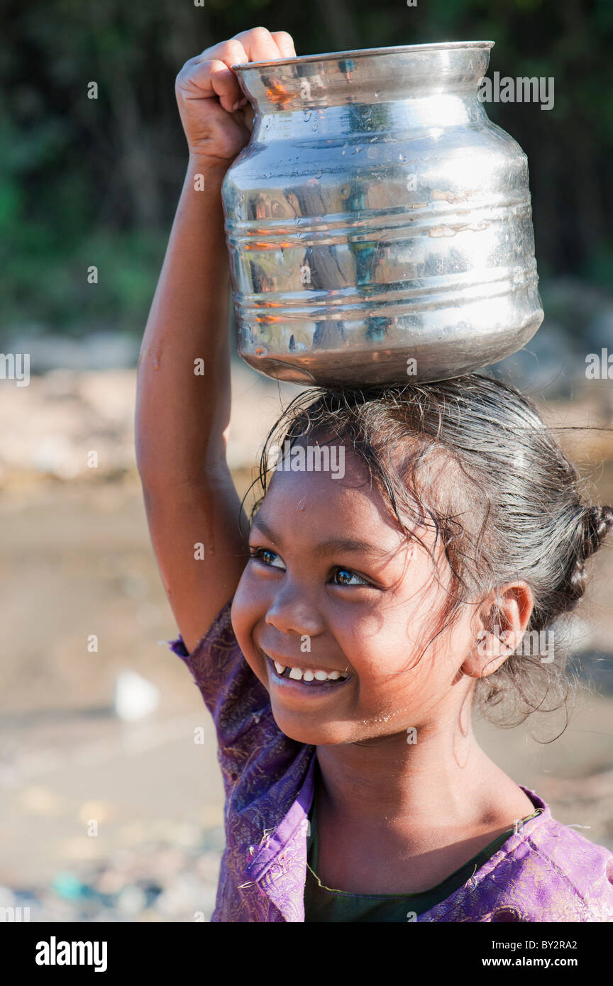 Sorridendo felice villaggio indiano ragazza che porta una pentola d'acqua. Andhra Pradesh, India Foto Stock