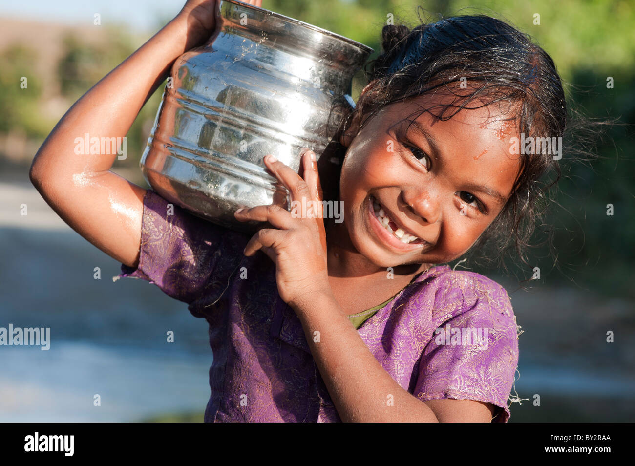 Sorridendo felice villaggio indiano ragazza che porta una pentola d'acqua. Andhra Pradesh, India Foto Stock