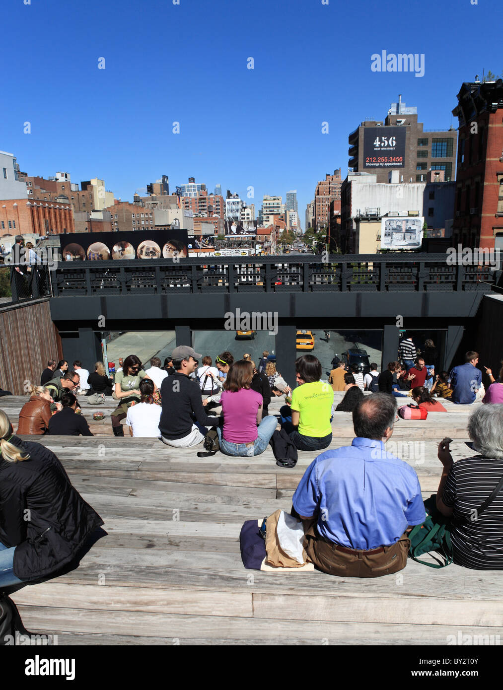 Persone fare picnic sui gradini in legno all'interno di New York alta linea parco pubblico. Foto Stock