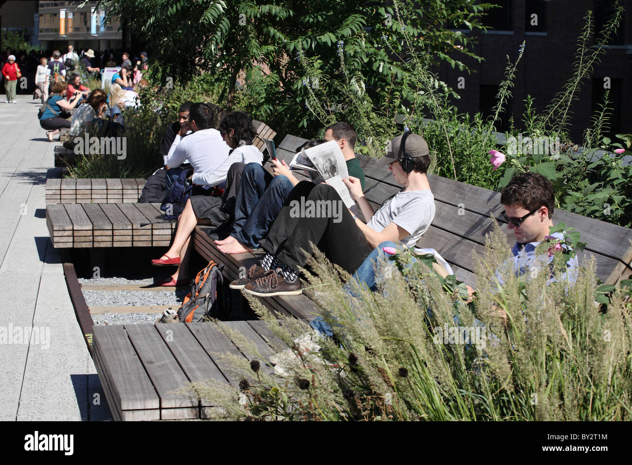 I giovani la lettura e il relax al sole, New York High Line parco pubblico, Manhattan. Foto Stock