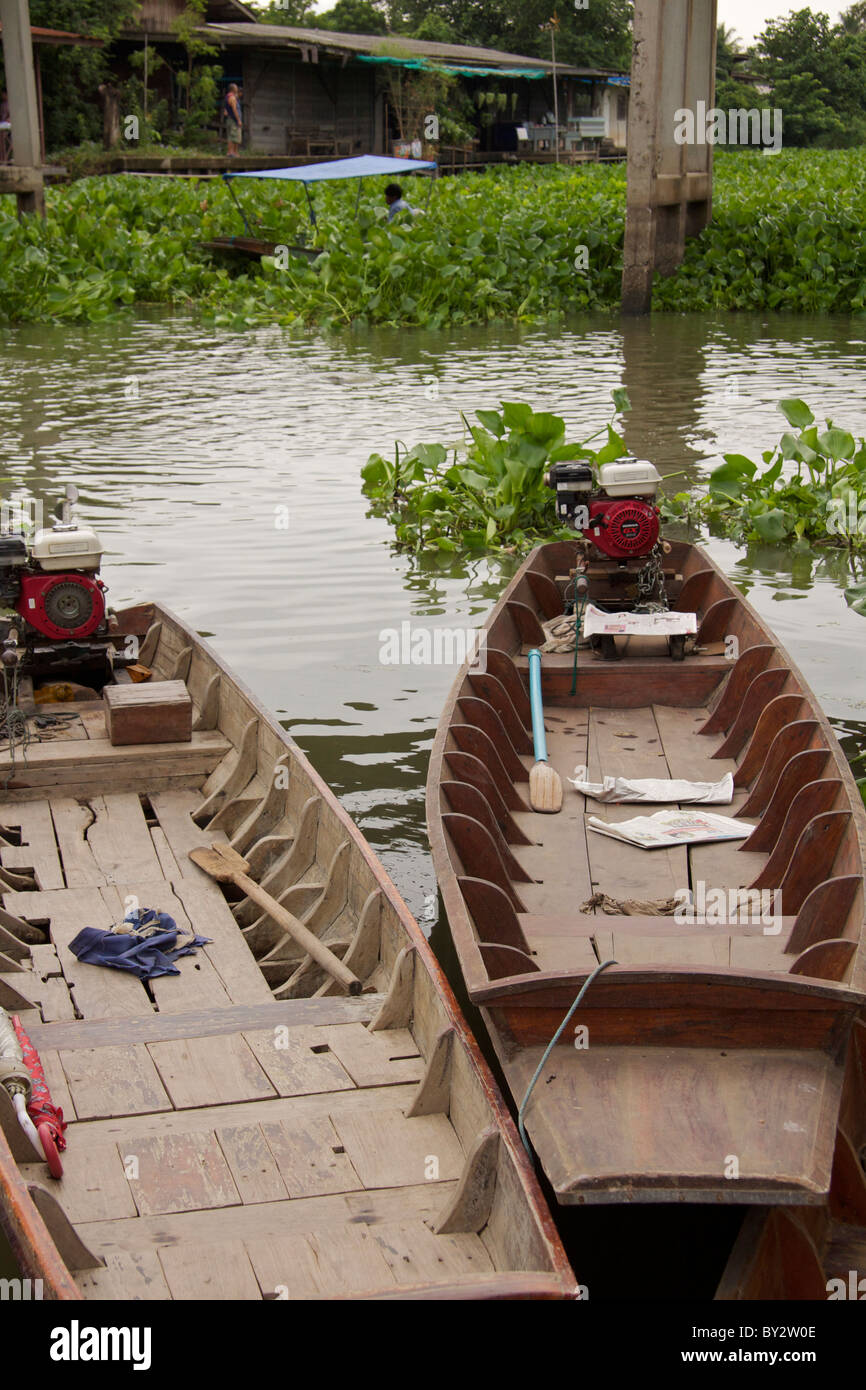 In legno tradizionali barche sul canale con acqua giacinti galleggiante sul canal a Klong Mahasawasdi Foto Stock