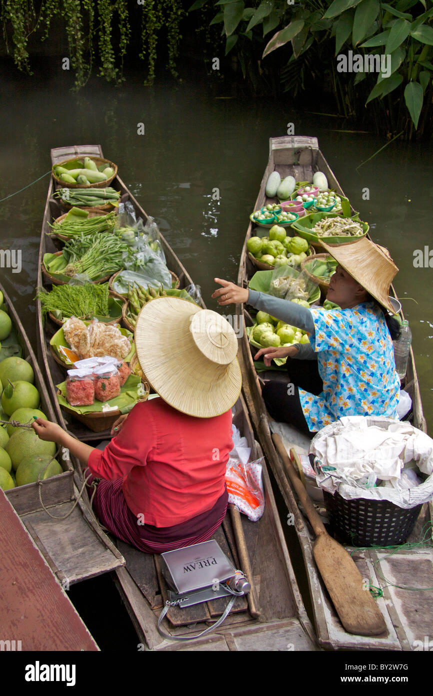 Due signore vendono frutta e altri prodotti alimentari nei tradizionali barche di legno su un canale laterale in 'Thai Cultural Village' Foto Stock