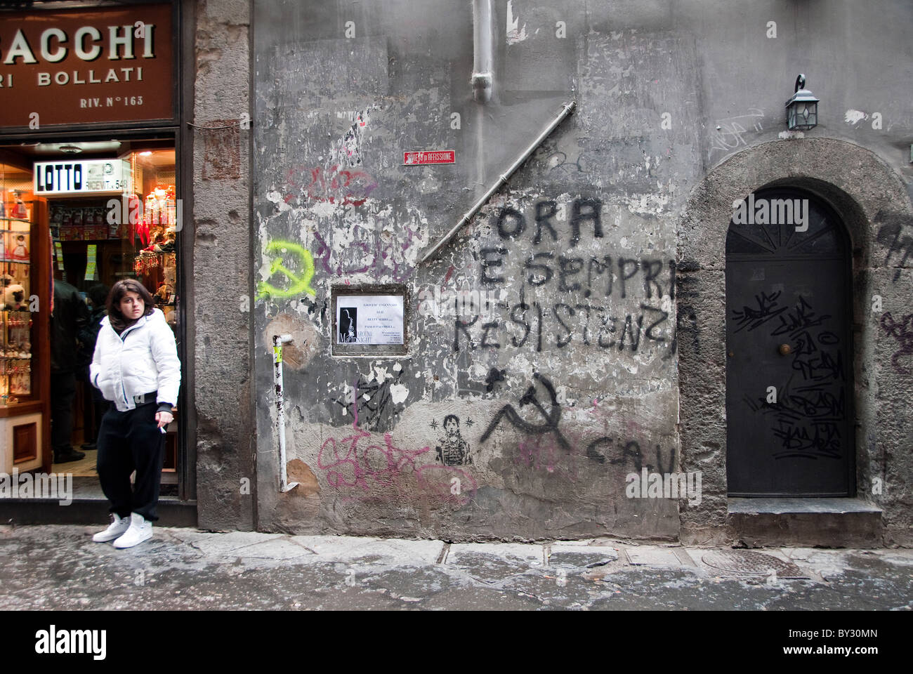 Local ragazza italiana di fumare su un angolo di strada contro una parete della street art e Graffiti a Napoli, Italia Foto Stock