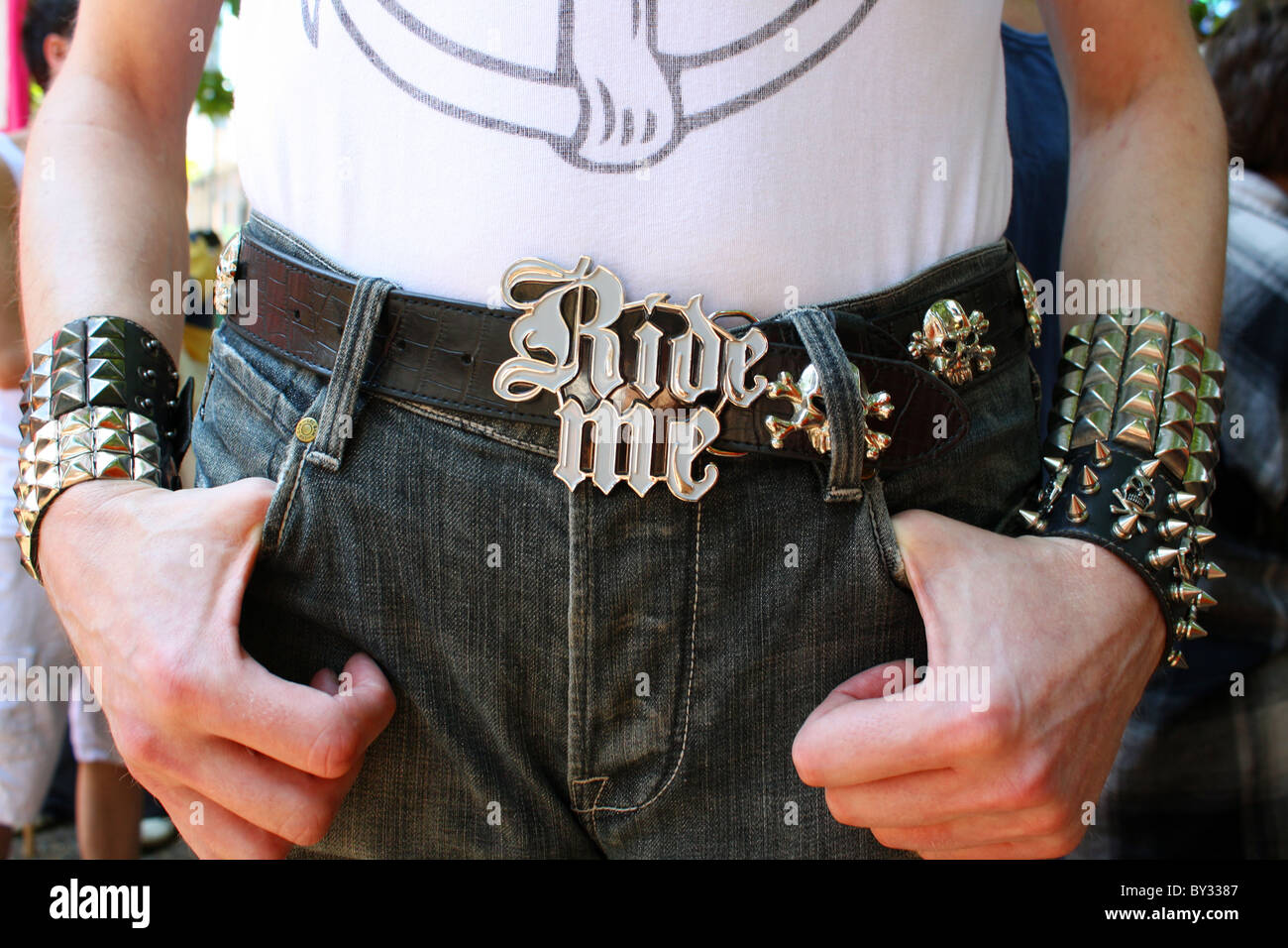 Vista ritagliata di un uomo con il suo pollice nella sua tasca che indossa una grande novità della fibbia della cintura di sicurezza Foto Stock