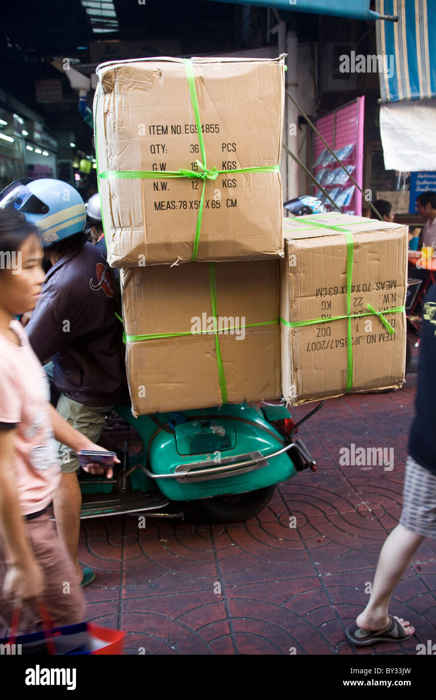 Corriere Rider su Classic Vespa scooter che trasportano enormi scatole Bangkok Chinatown Foto Stock