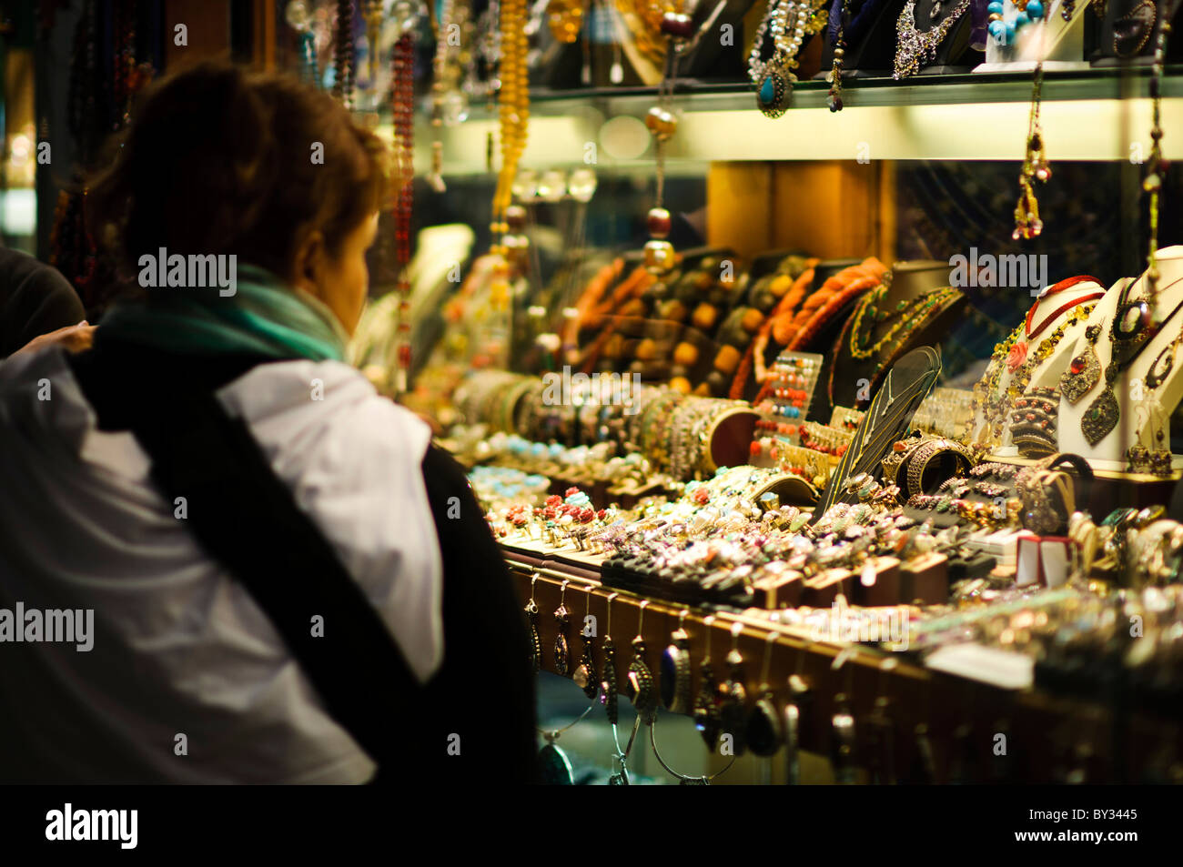 Un acquirente si ammira la mercanzia di uno dei tanti negozi di Gioielleria all'interno di Istanbul storica Grand Bazaar Foto Stock