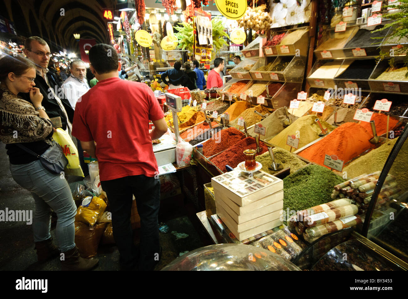 Spice Bazaar spezie ed erbe Istanbul Turchia // ISTANBUL, Turchia - i clienti acquistano spezie vicino al Bazaar delle spezie (noto anche come Bazaar egiziano) a Istanbul. Il Bazar delle spezie, costruito nel 1660 come parte del complesso della nuova Moschea, è uno dei più antichi mercati coperti di Istanbul e un importante centro per il commercio delle spezie. Il mercato ospita decine di negozi che vendono spezie tradizionali turche, erbe, tè e altri prodotti culinari. Situato nel quartiere di Eminönü vicino al Corno d'Oro, il bazar attira sia i residenti locali che i visitatori internazionali. La posizione strategica del mercato ha fatto Foto Stock