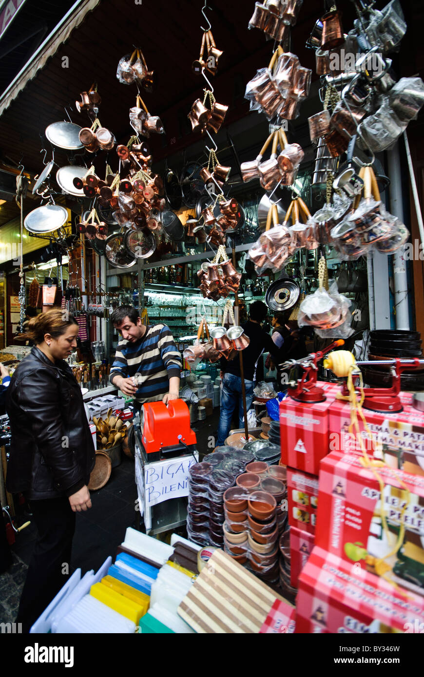 Bazar delle spezie teiere e utensili da cucina in rame Istanbul // ISTANBUL, Turchia — Un negozio espone çaydanlık di rame (teiere turche tradizionali) e altri utensili da cucina nel bazar delle spezie (noto anche come bazar egiziano) di Istanbul. Il çaydanlık è costituito da due vasi impilati utilizzati nel tradizionale metodo di estrazione del tè turco, con la pentola più grande per bollire l'acqua e la pentola più piccola per preparare il tè concentrato. Il Bazar delle spezie, costruito nel 1664, è uno dei più antichi mercati coperti di Istanbul e tradizionalmente è servito come centro per il commercio di spezie e erbe medicinali. Il mercato è costituito da 88 Foto Stock