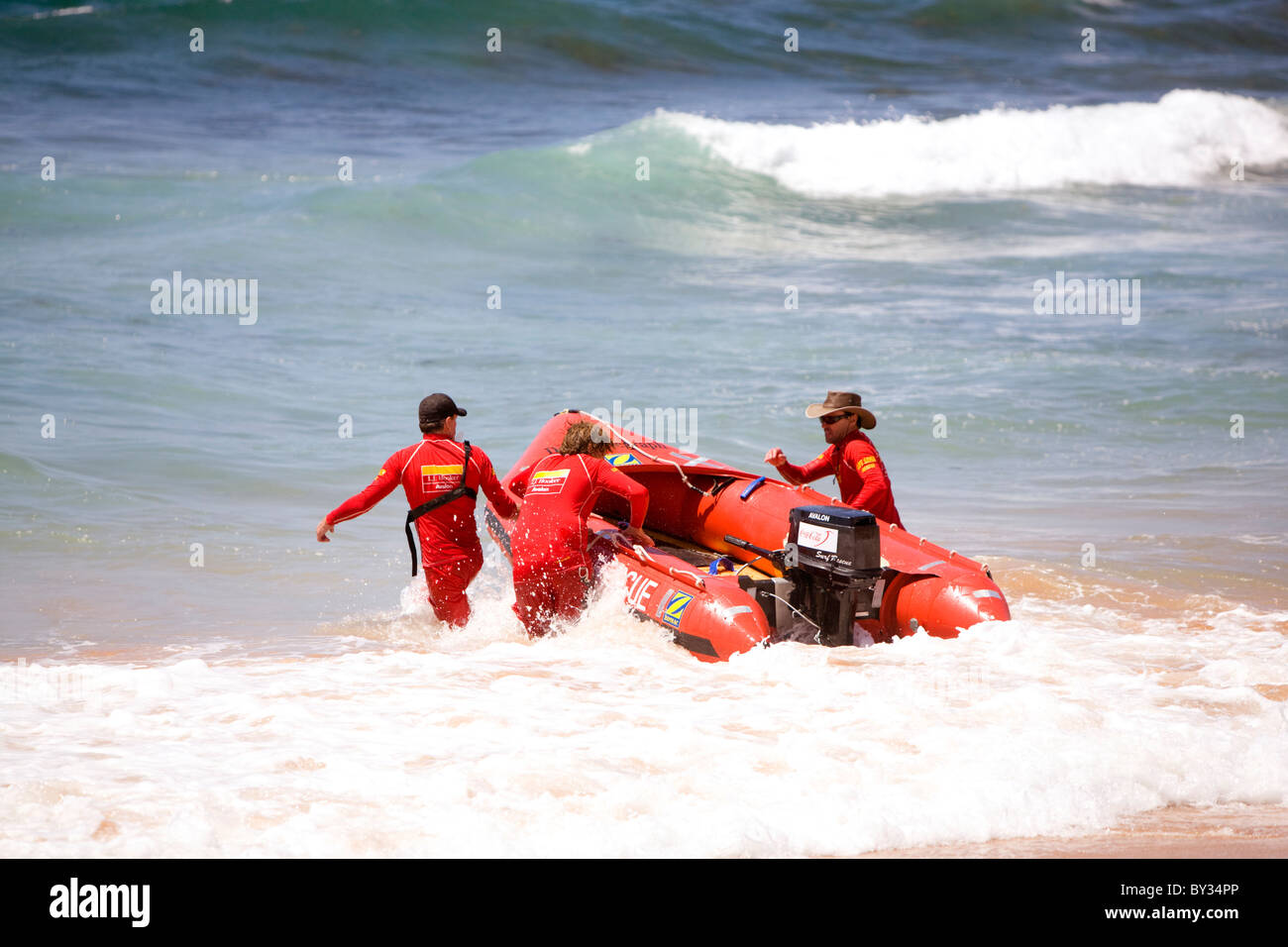 Tre bagnini maschio a piedi la loro barca di salvataggio in mare,Sydney , Australia Foto Stock